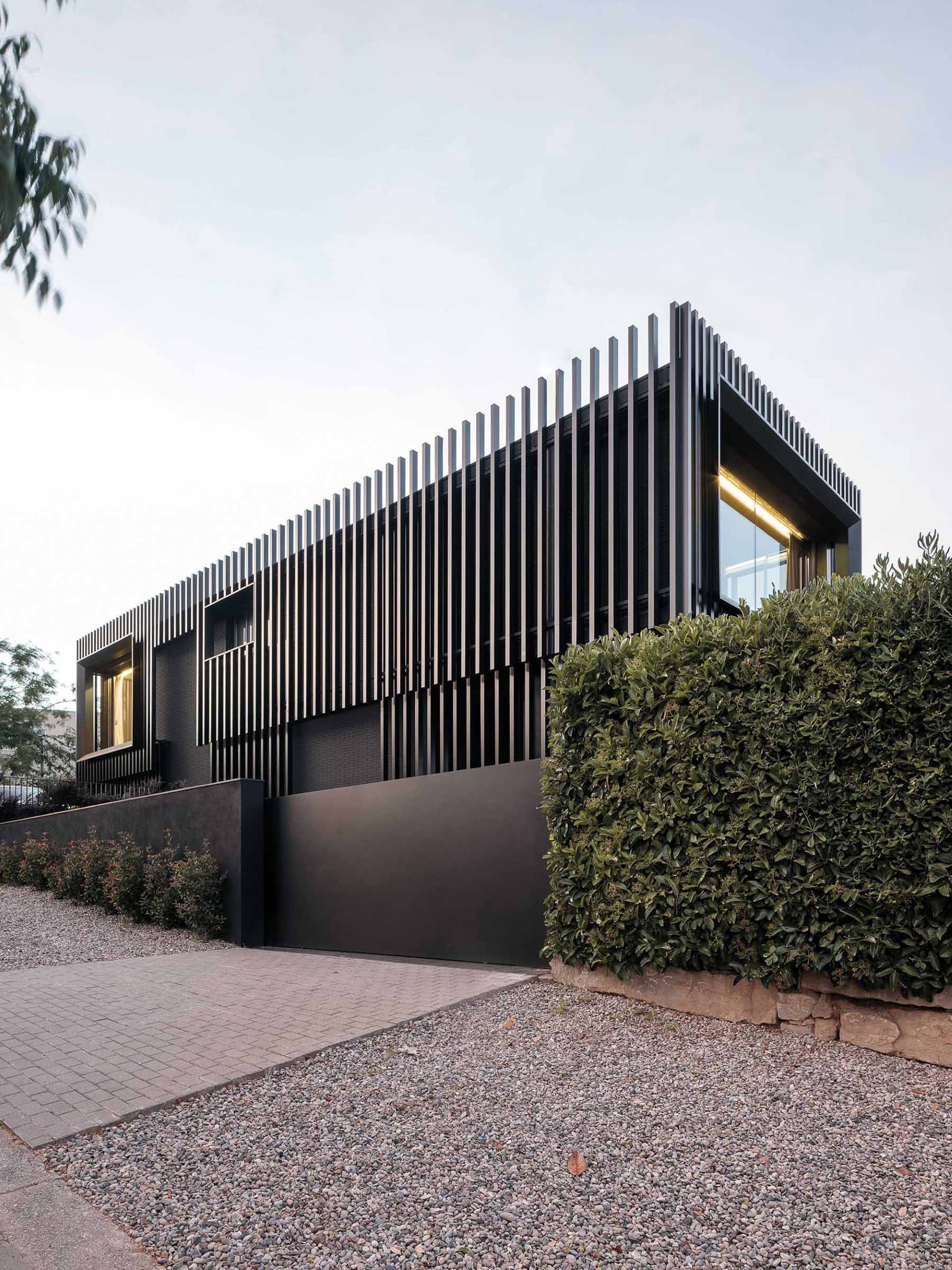 A modern black house has vertical planes that wrap around its exterior, creating a monochromatic appearance.