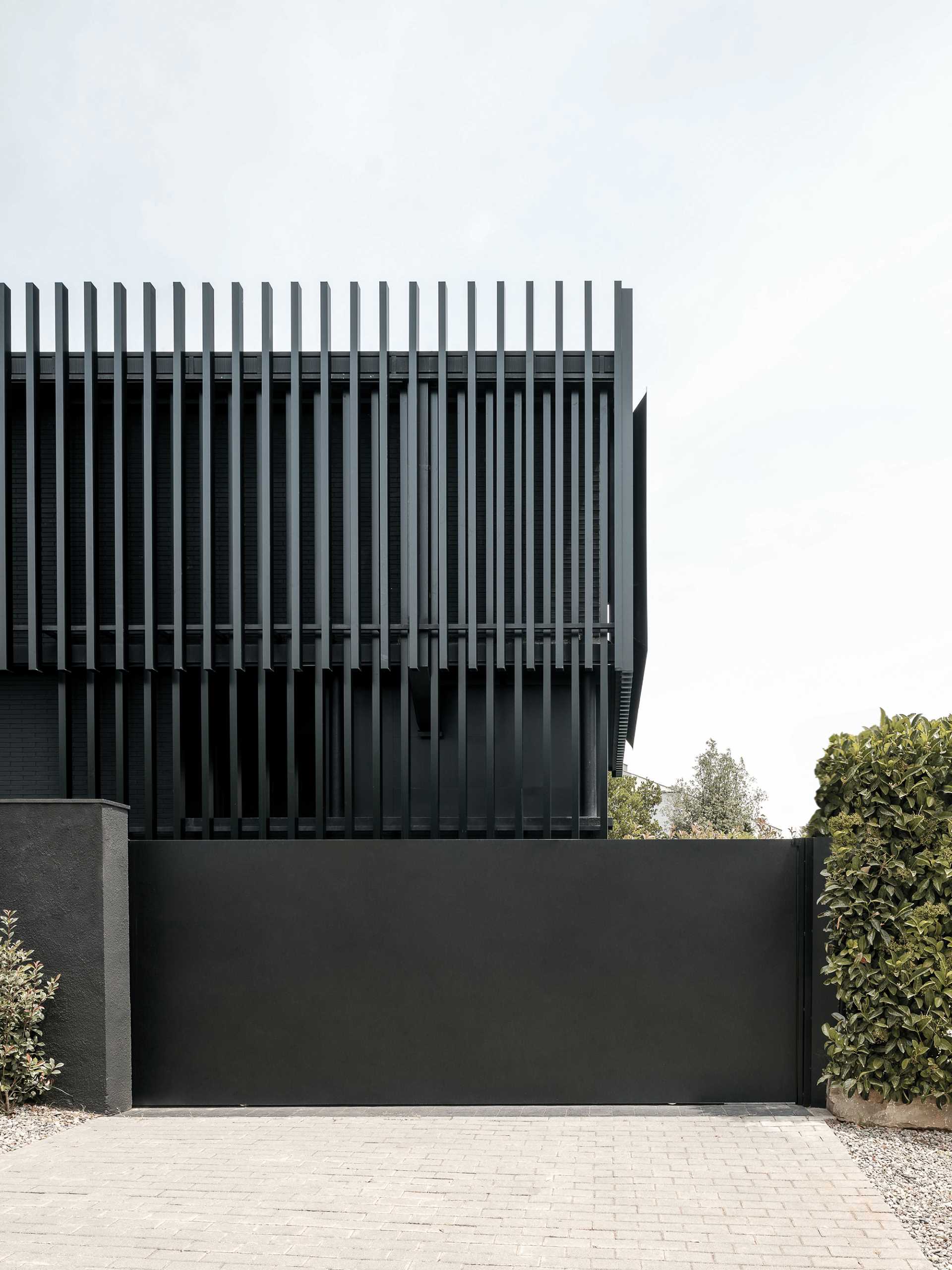 A modern black house has vertical planes that wrap around its exterior, creating a monochromatic appearance.