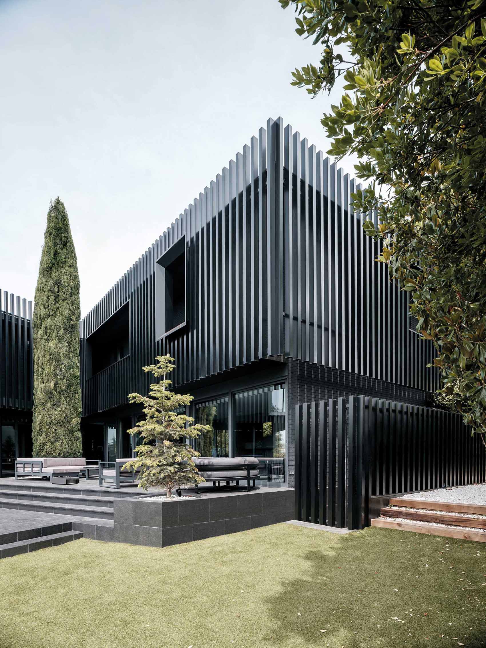 A modern black house has vertical planes that wrap around its exterior, creating a monochromatic appearance.