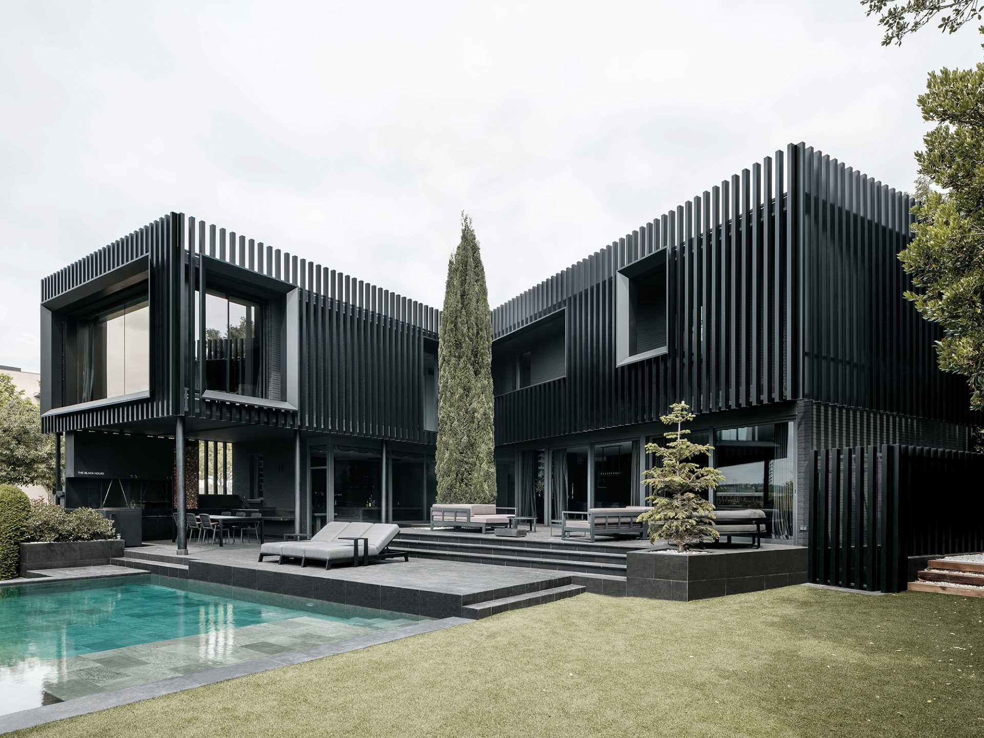 A modern black house has vertical planes that wrap around its exterior, creating a monochromatic appearance.