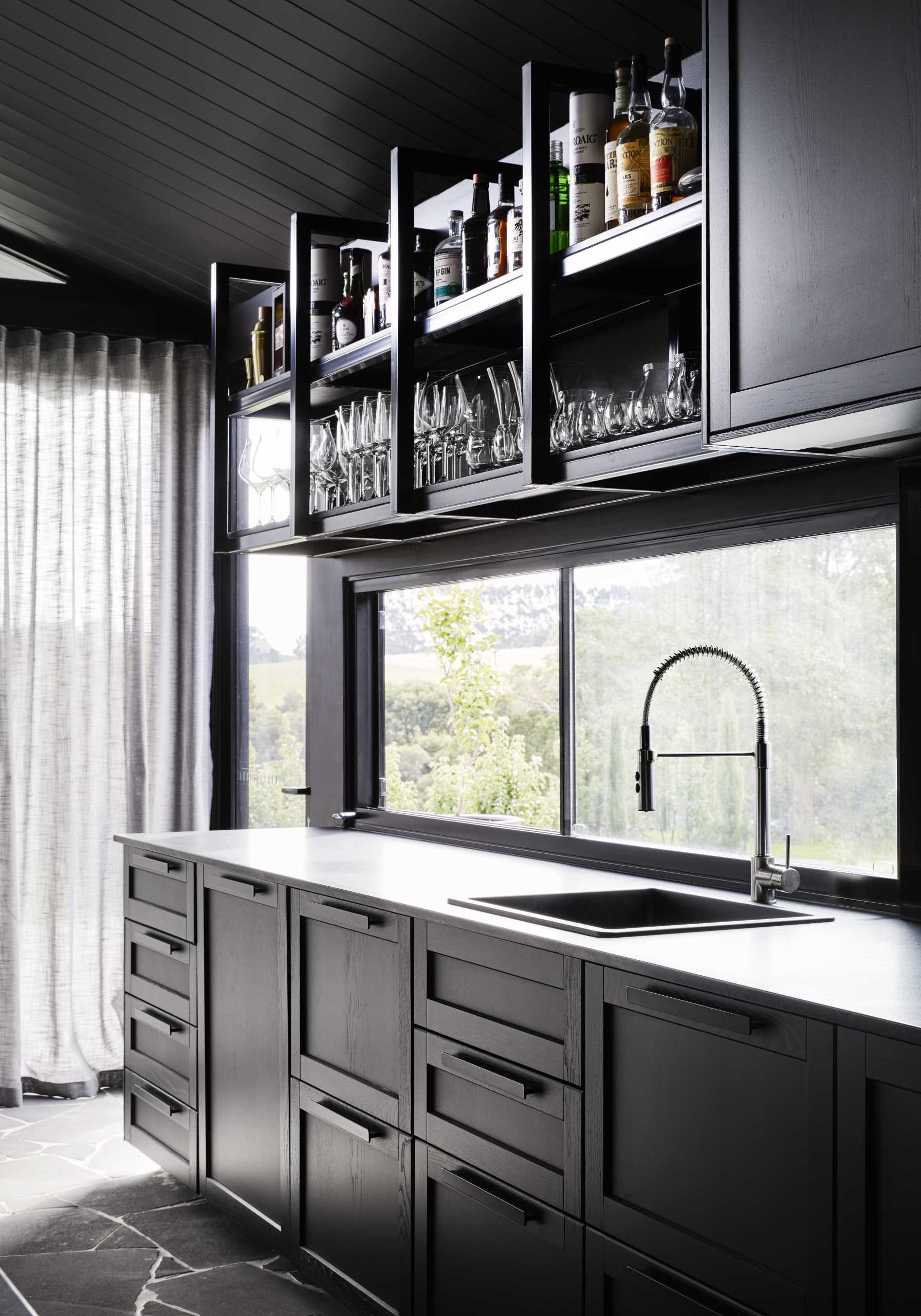 A modern black kitchen that's designed as a full-sized bar with a gentleman's club aesthetic.