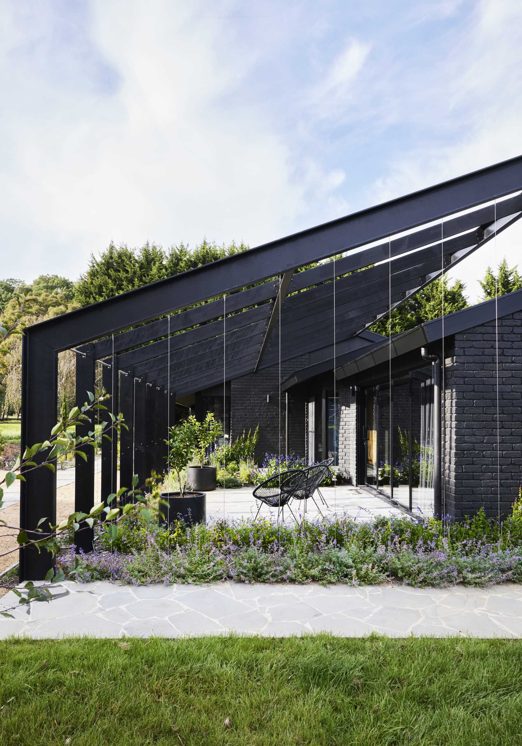 A modern farmhouse with a courtyard that will become enclosed with plants over time.