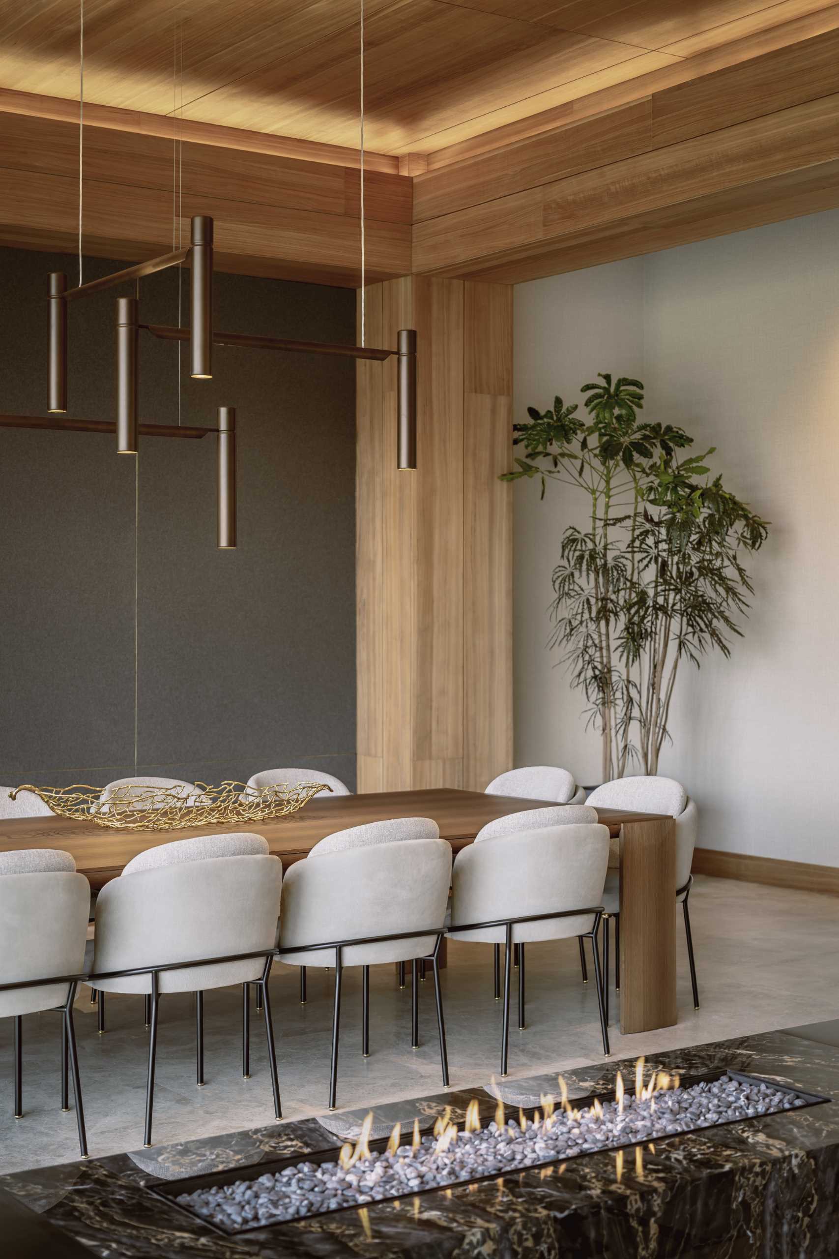 A modern dining room with a dark accent wall and hidden lighting that showcases the wood ceiling.