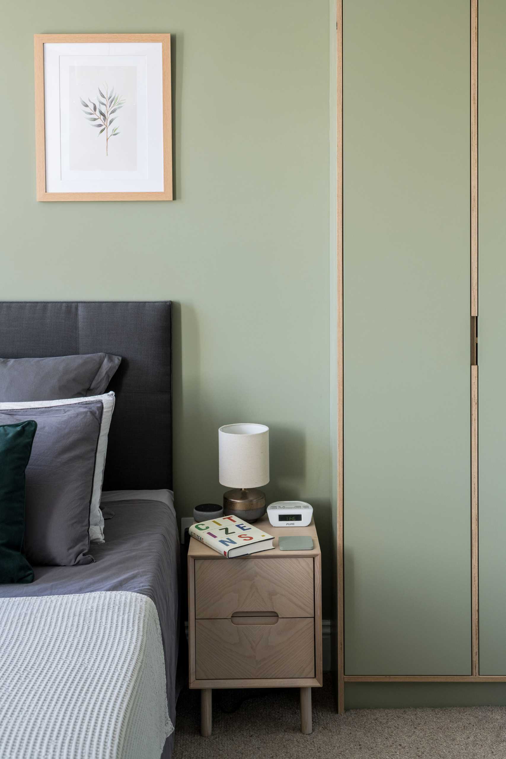 In this modern bedroom, matte green was the chosen color, and is featured on the walls as well as the closets. Wood accents provide a natural contrasting element.