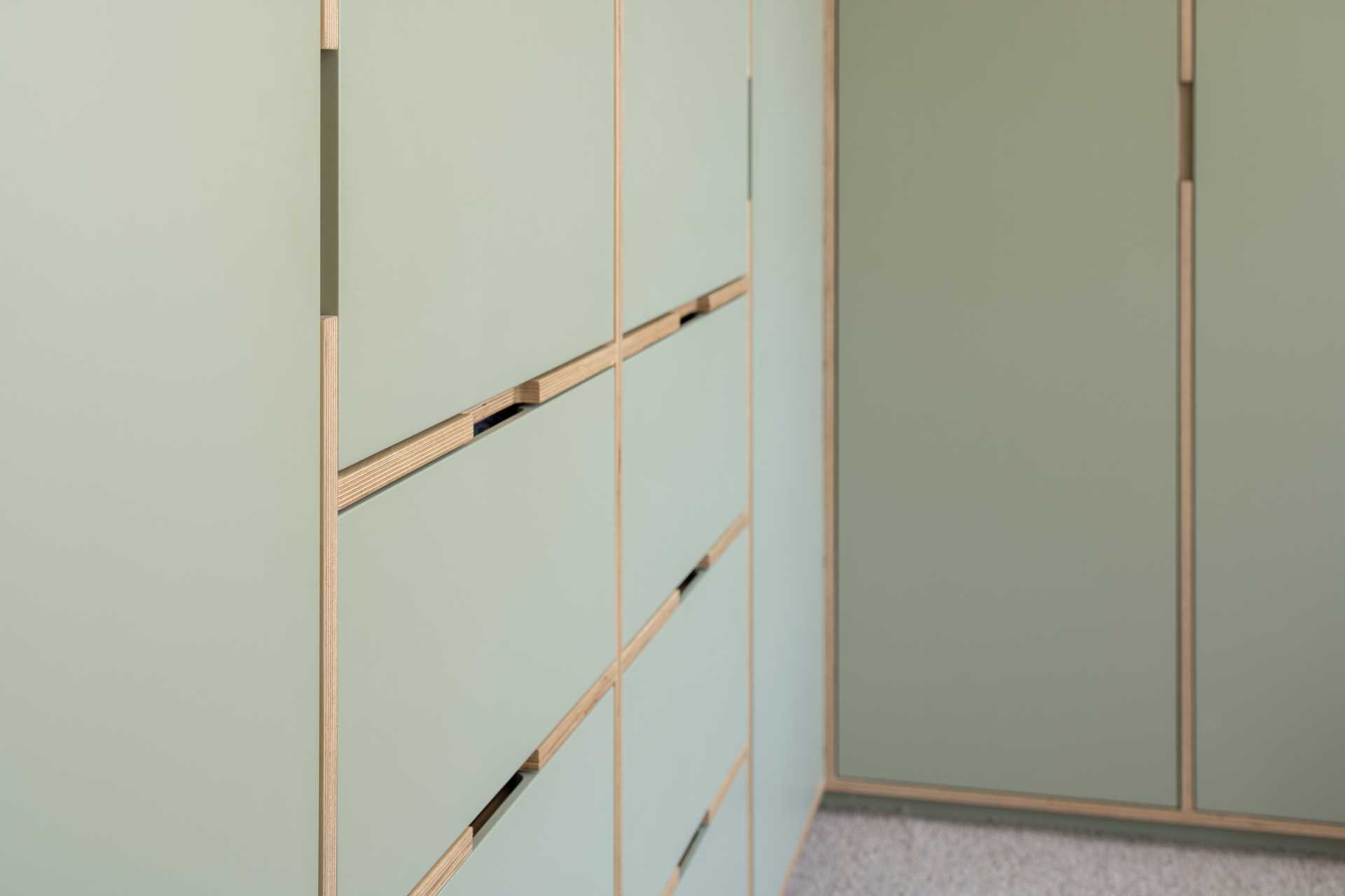 In this modern bedroom, matte green was the chosen color, and is featured on the walls as well as the closets. Wood accents provide a natural contrasting element.