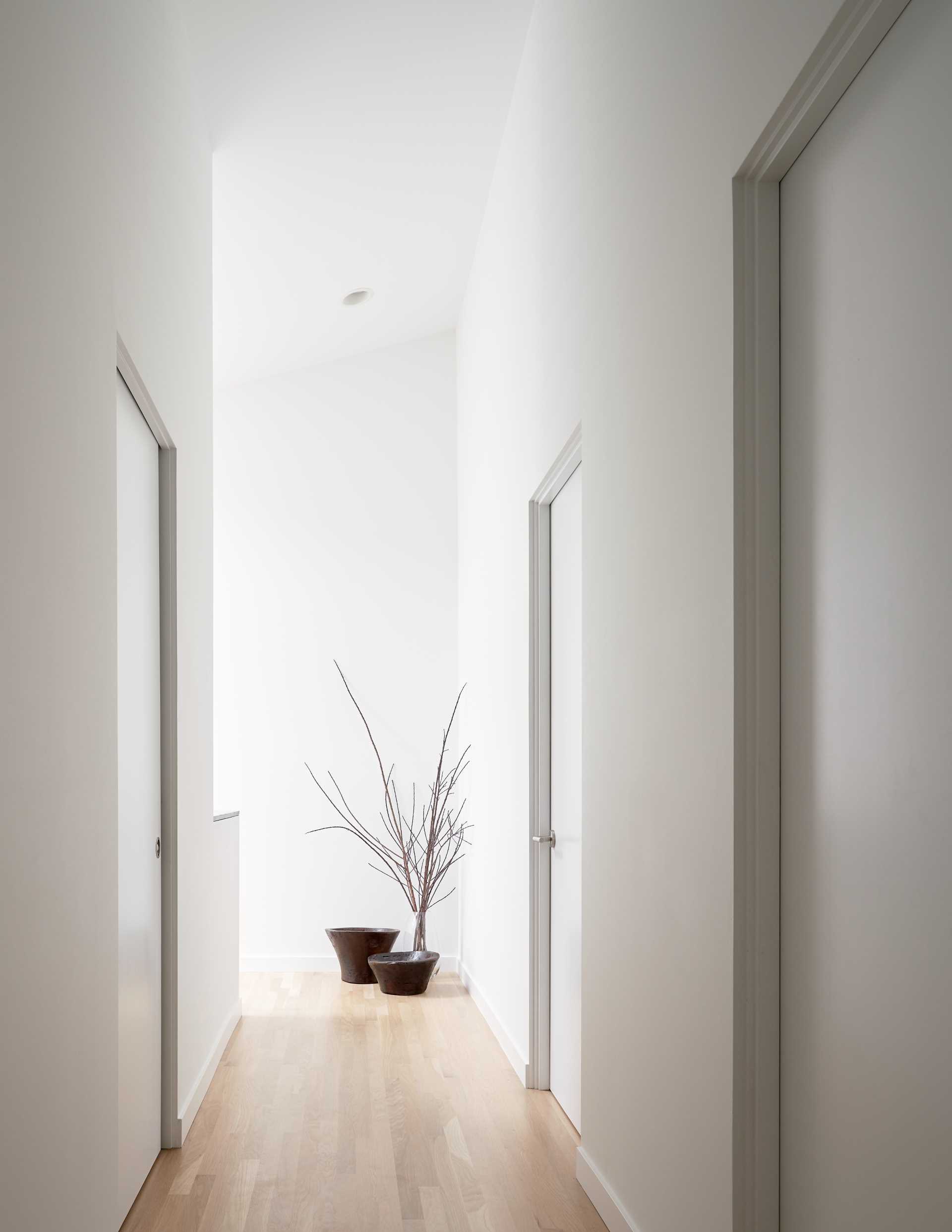 A modern hallway with white walls and wood flooring.