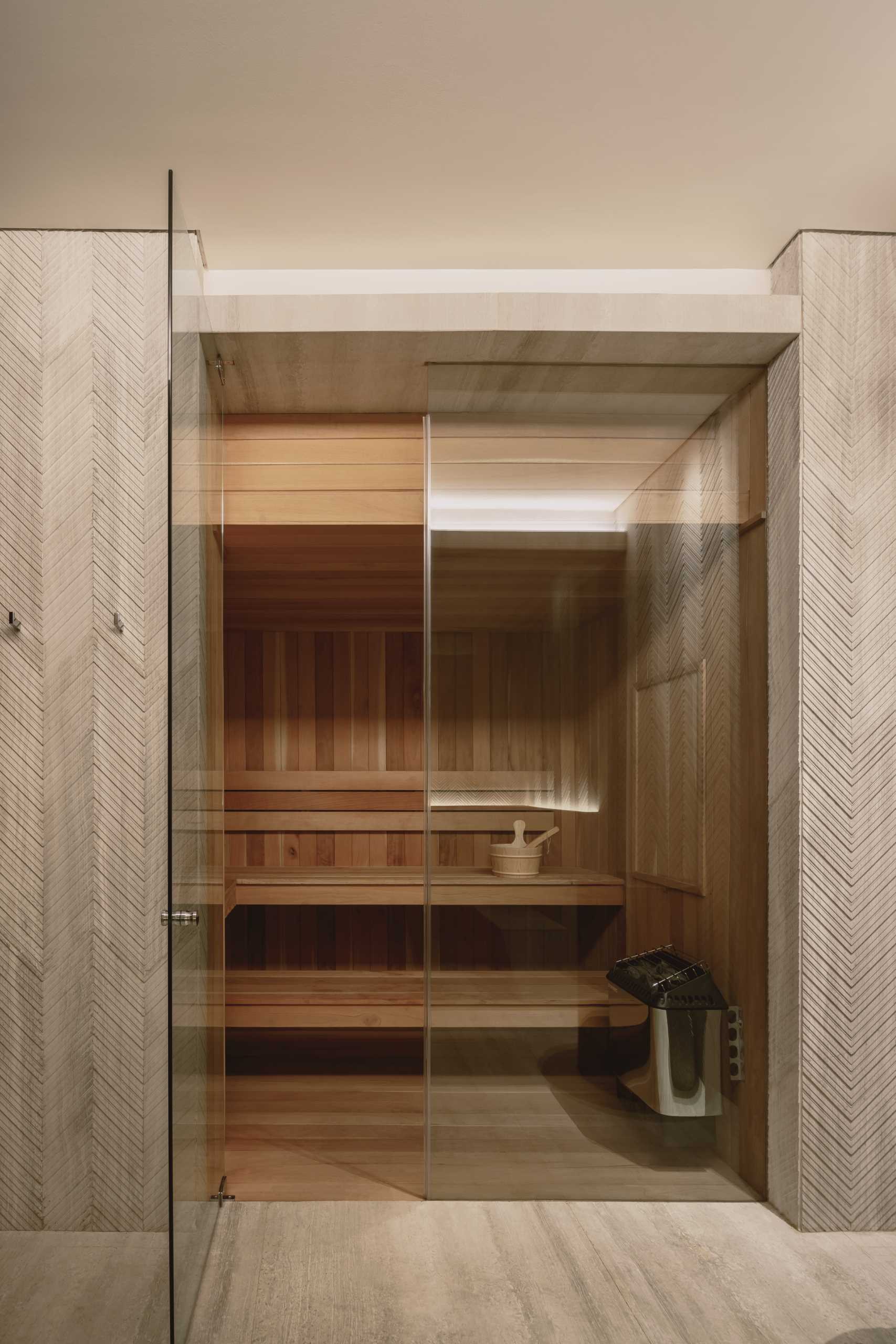 A modern home with a wood-lined sauna that has a glass door.