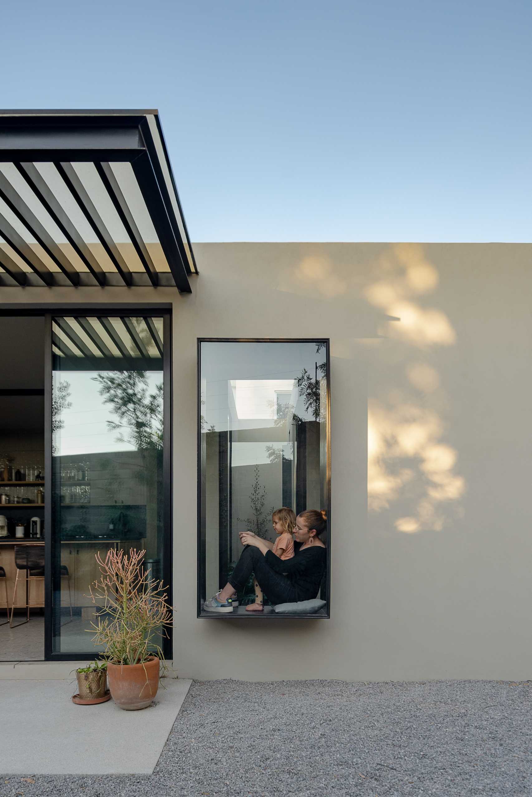 A protruding black-framed window creates space inside for a window seat.