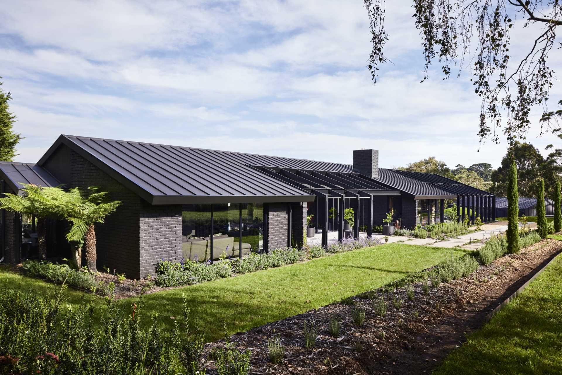 A paved pathway leads past the courtyard and garden, and to the recessed entryway and front door.