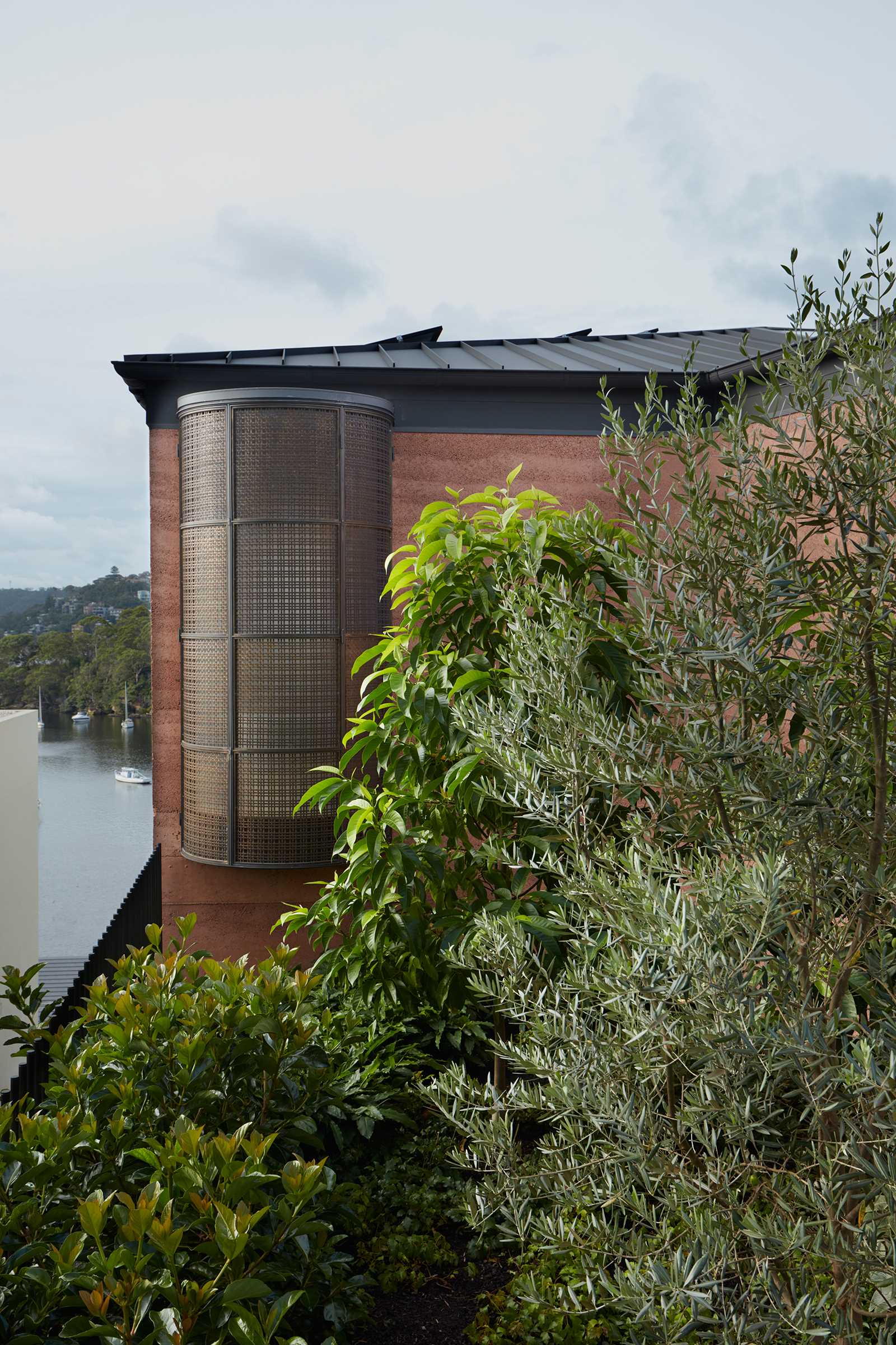 A modern house with rammed earth walls and a curved window element.