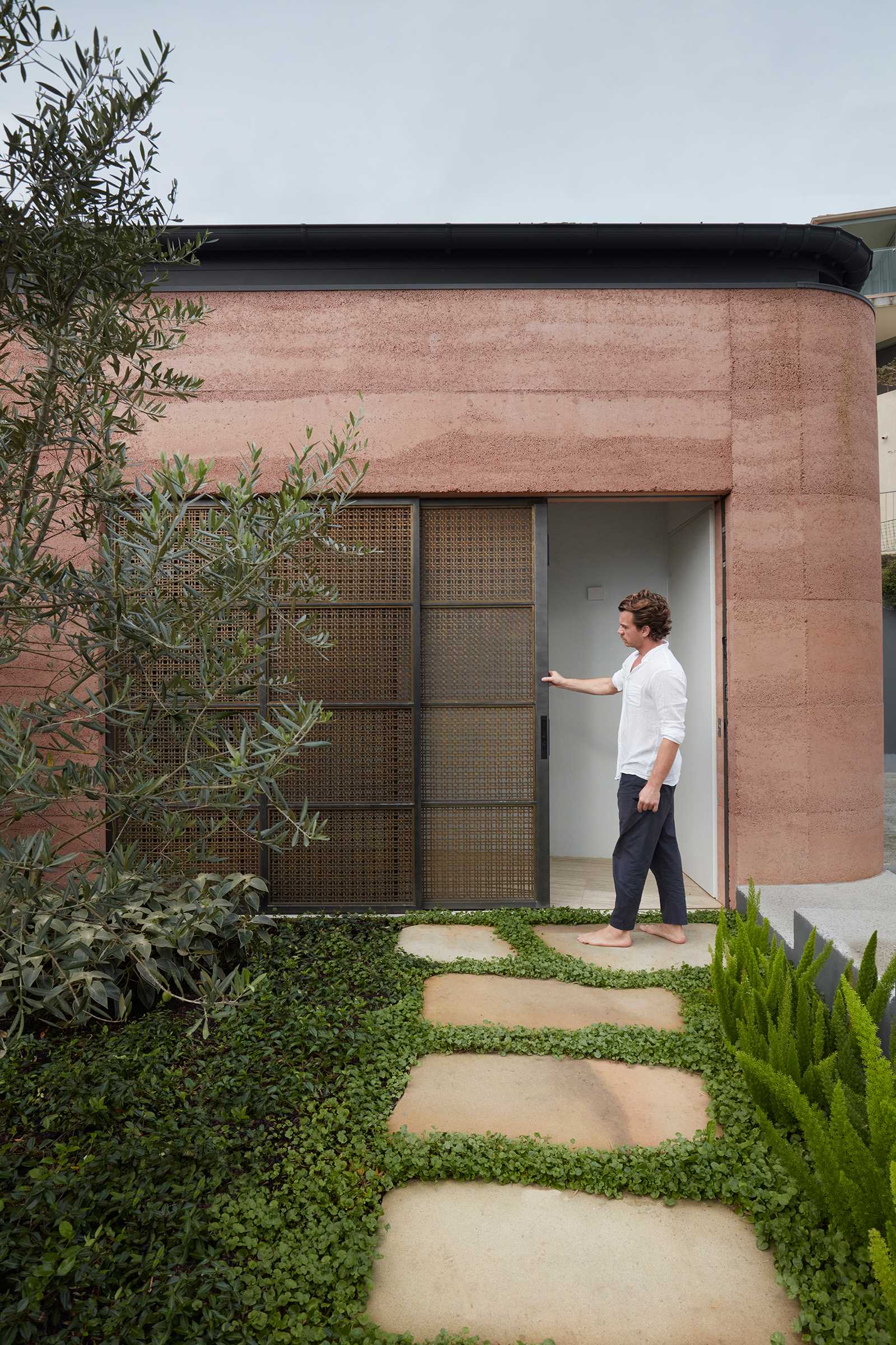 Visitors are greeted by the top level of this modern house, where the warm and welcoming colored rammed earth walls are clearly visible.