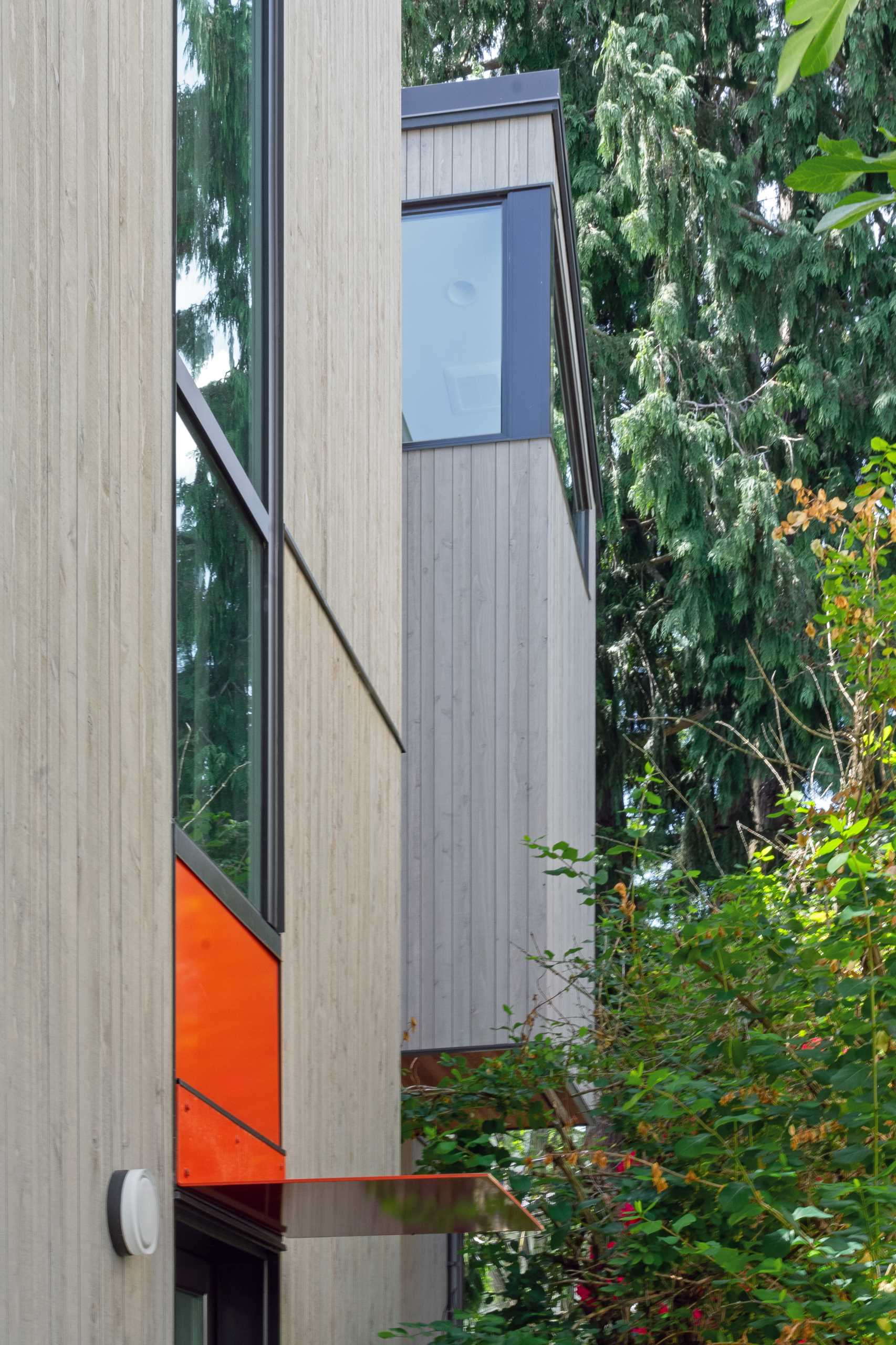 A modern house with wood siding, dark window frames, and colorful accents.