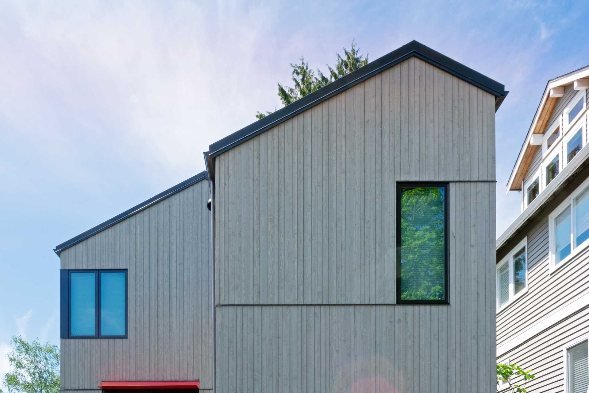 A modern house with wood siding and dark window frames.