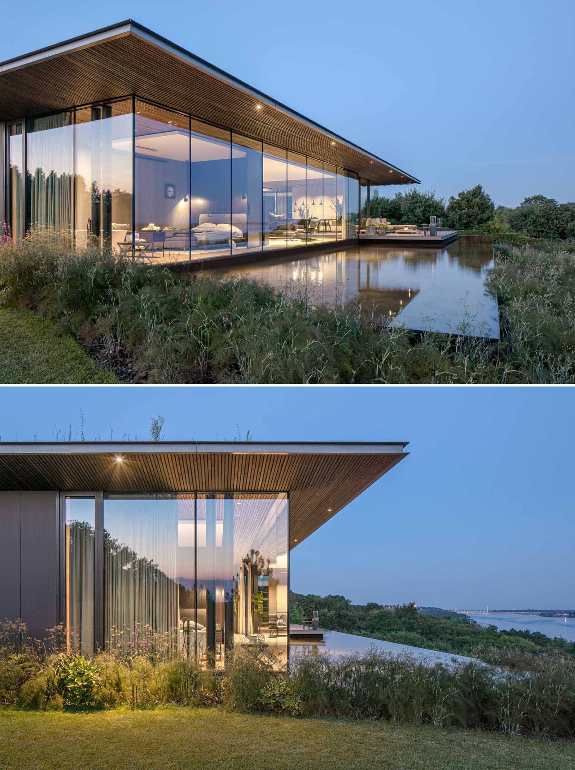 A modern house with floor-to-ceiling windows, a deck, and a water feature.