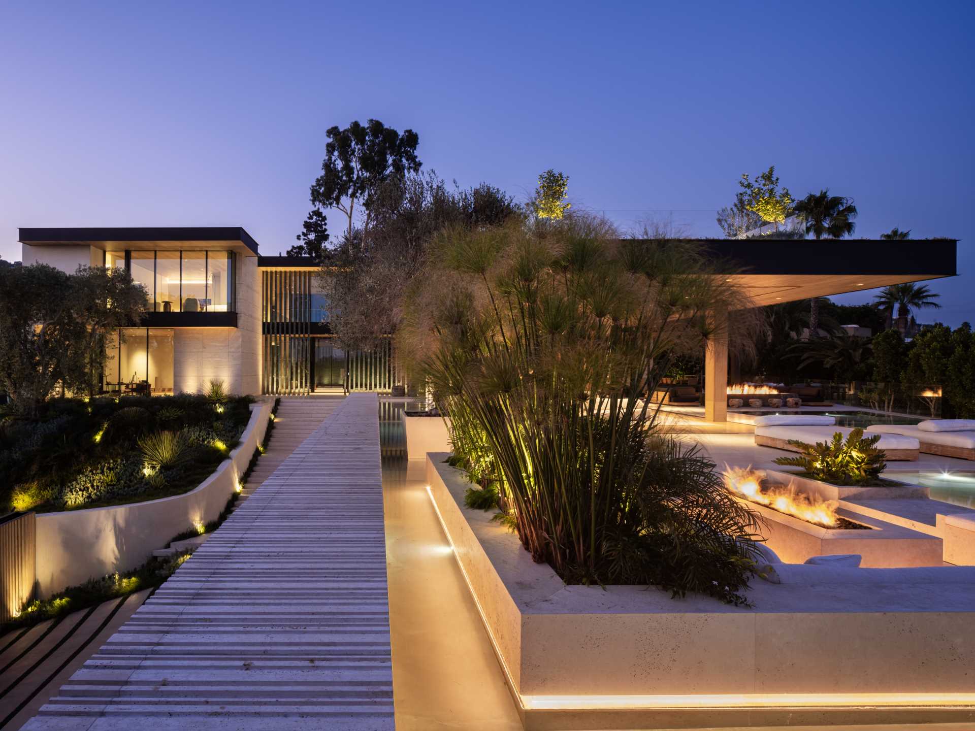 Outdoor lighting highlights the design features and landscaping of this house.