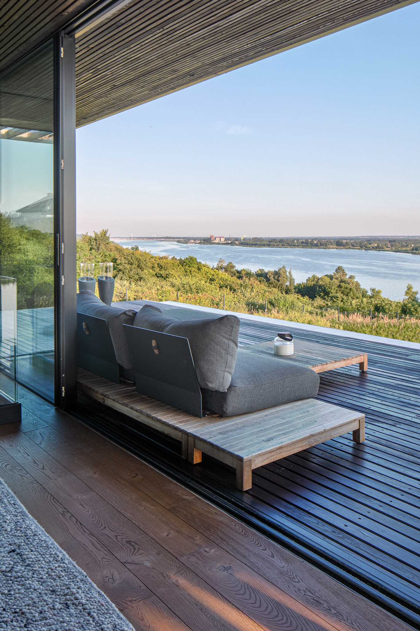 A modern home with a wall of windows, a deck, and a water feature.