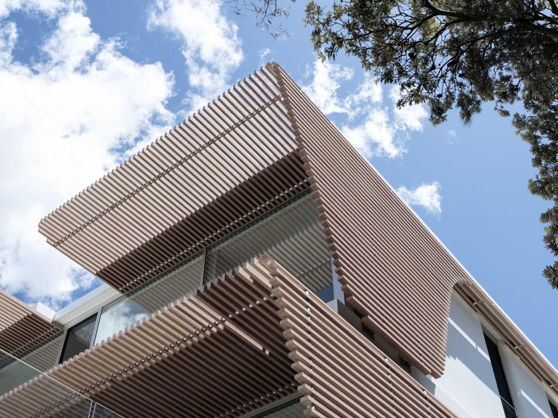 A modern home has wood-slat screens on its facade that create shading and privacy for the interior.