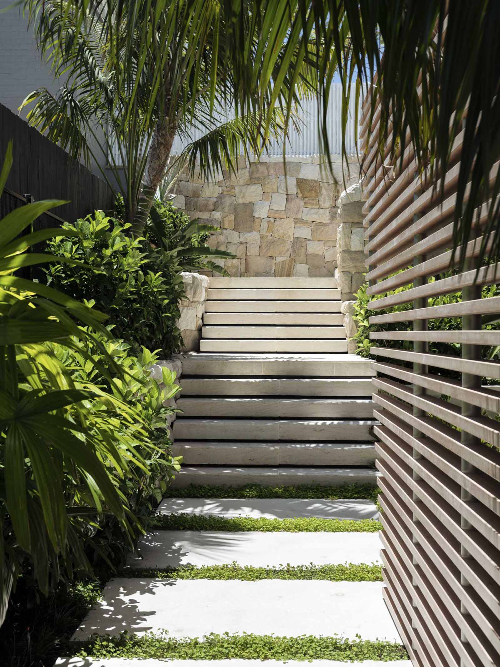 A modern home with landscaping that includes sandstone details and an abundance of indigenous plants.