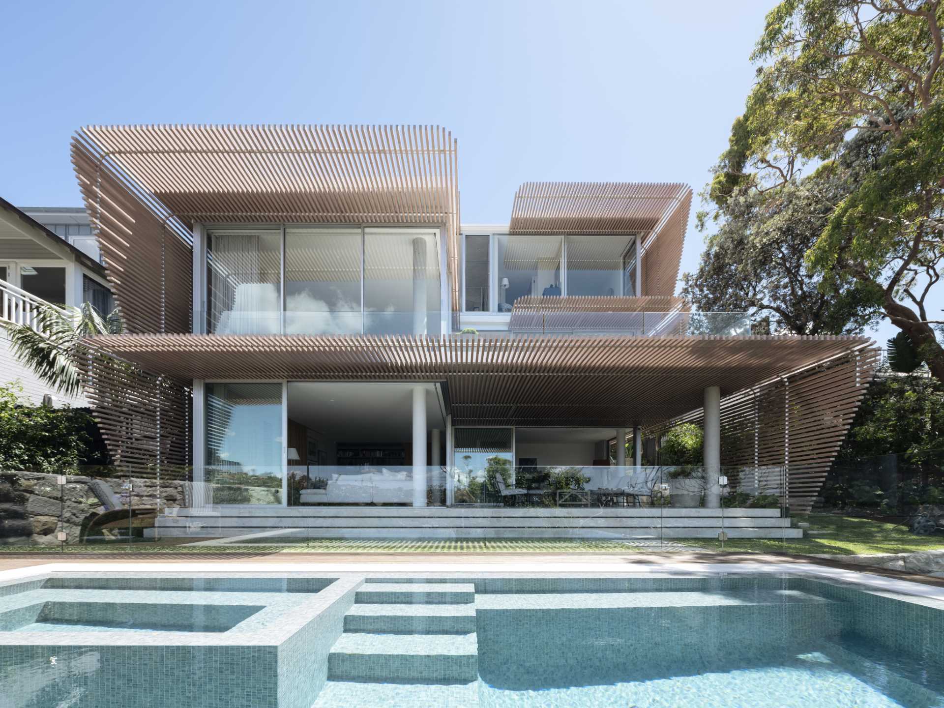 A modern home has wood-slat screens on its facade that create shading and privacy for the interior.