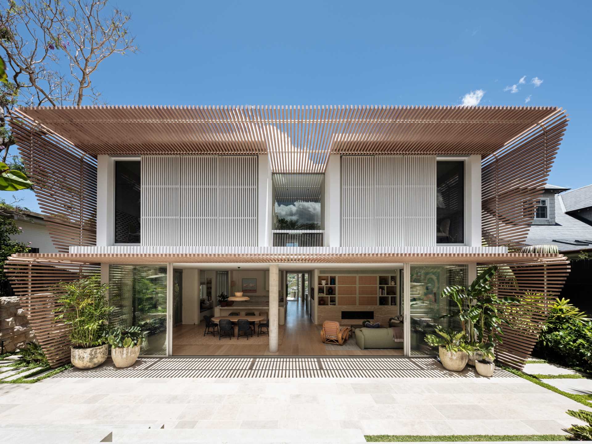 A modern home has wood-slat screens on its facade that create shading and privacy for the interior.