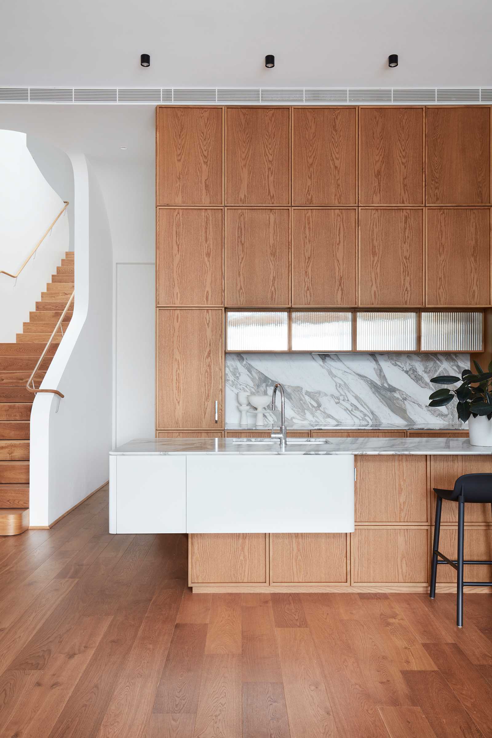A modern kitchen with wood cabinets and stone backsplash.