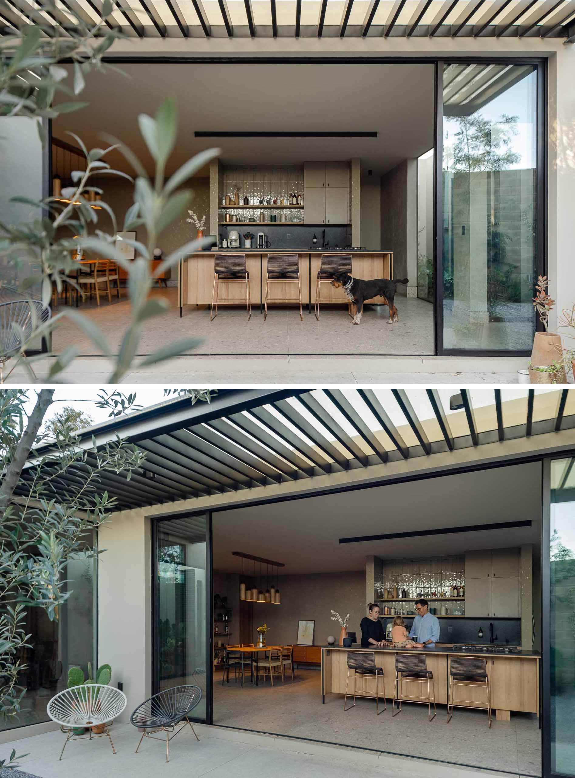 This modern and open-plan kitchen and dining area both feature wood, while the kitchen has a black backsplash that complements the window and door frames.