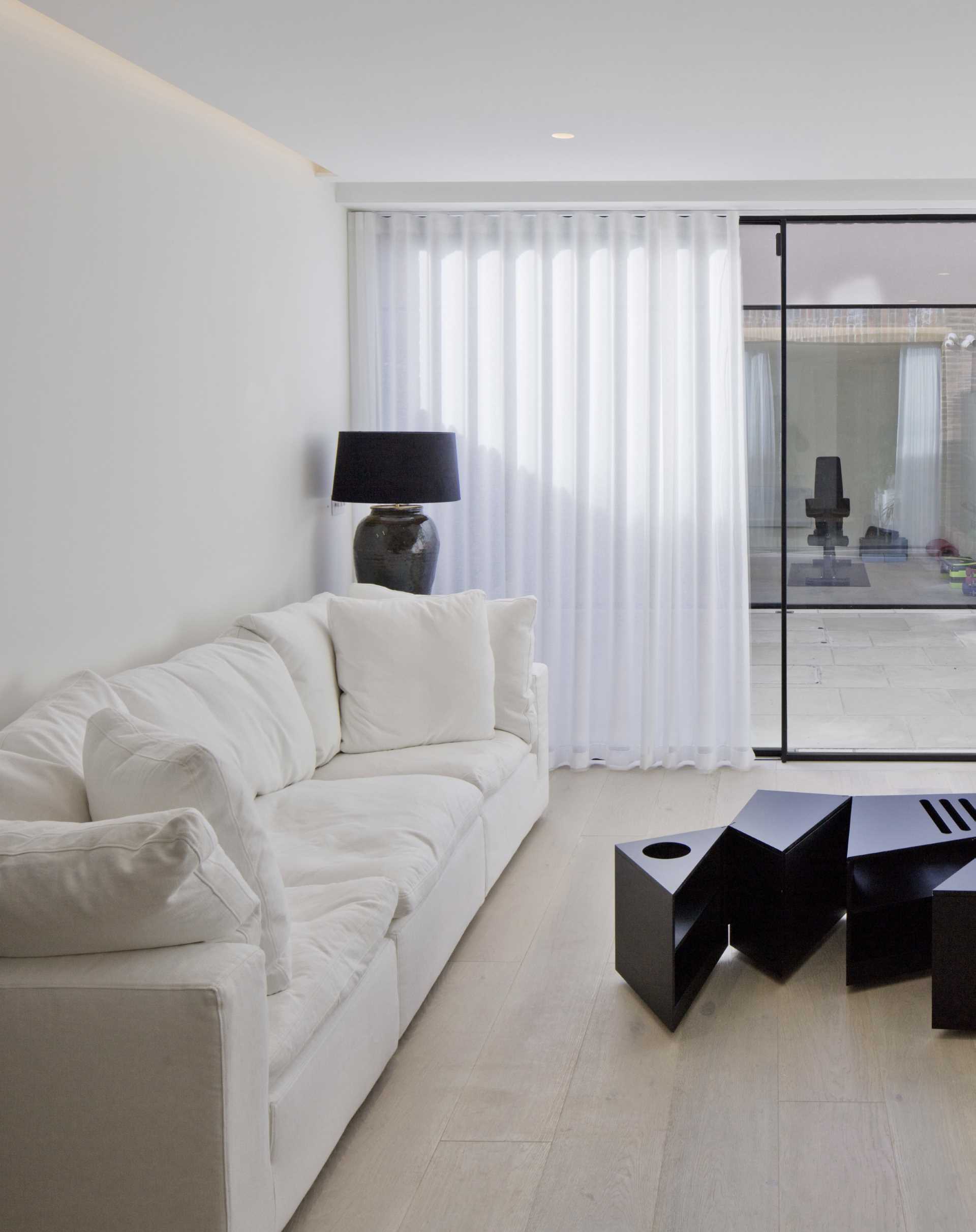 A modern white living room with access to a small outdoor space.