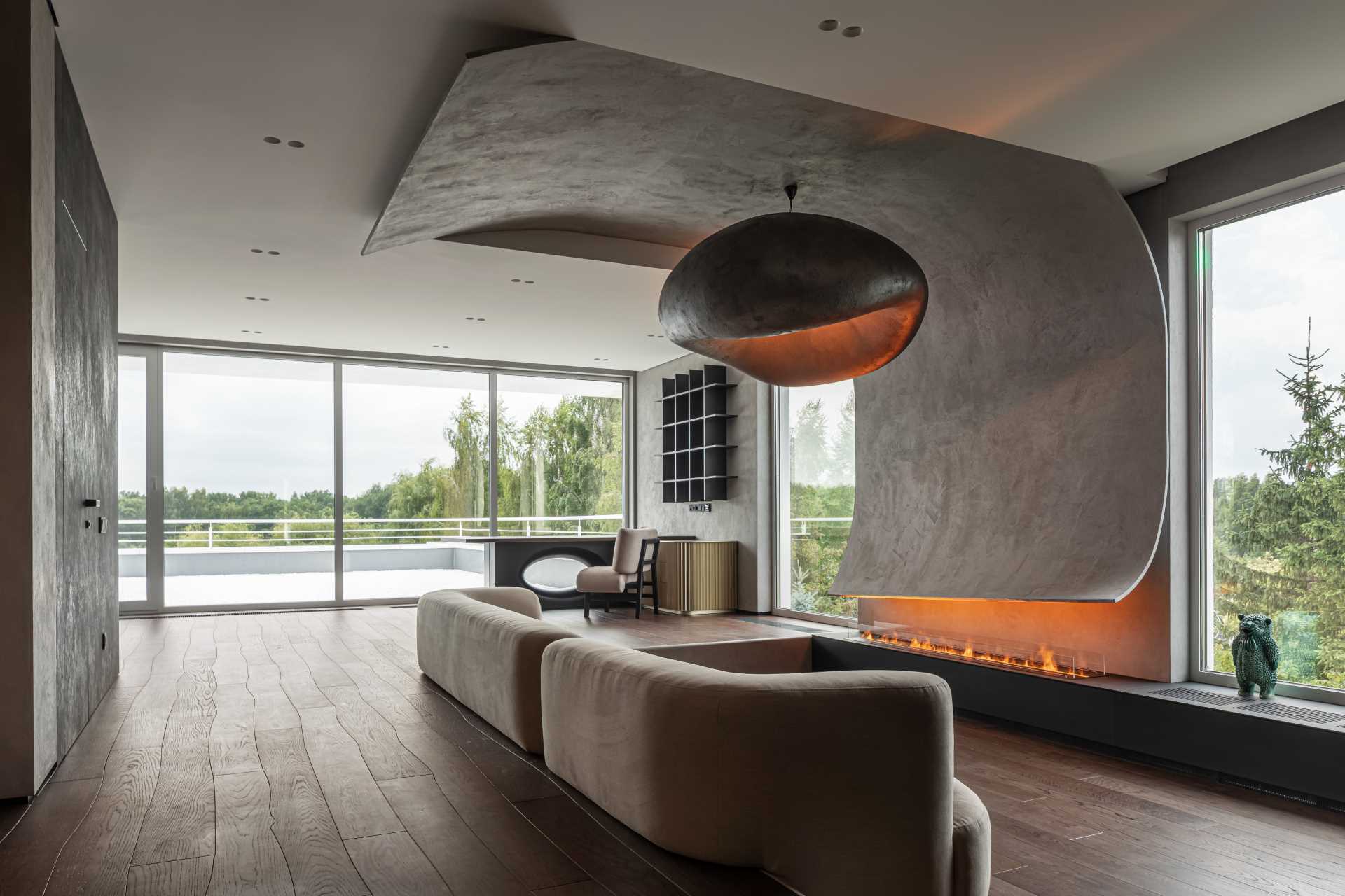 This modern living room has a sunken couch that neatly fits into the step-down, and faces the fireplace, while the focal point of the room is a curved section that's made of stone plaster. The curved accent wraps around the wall from above the fireplace to above the couch.