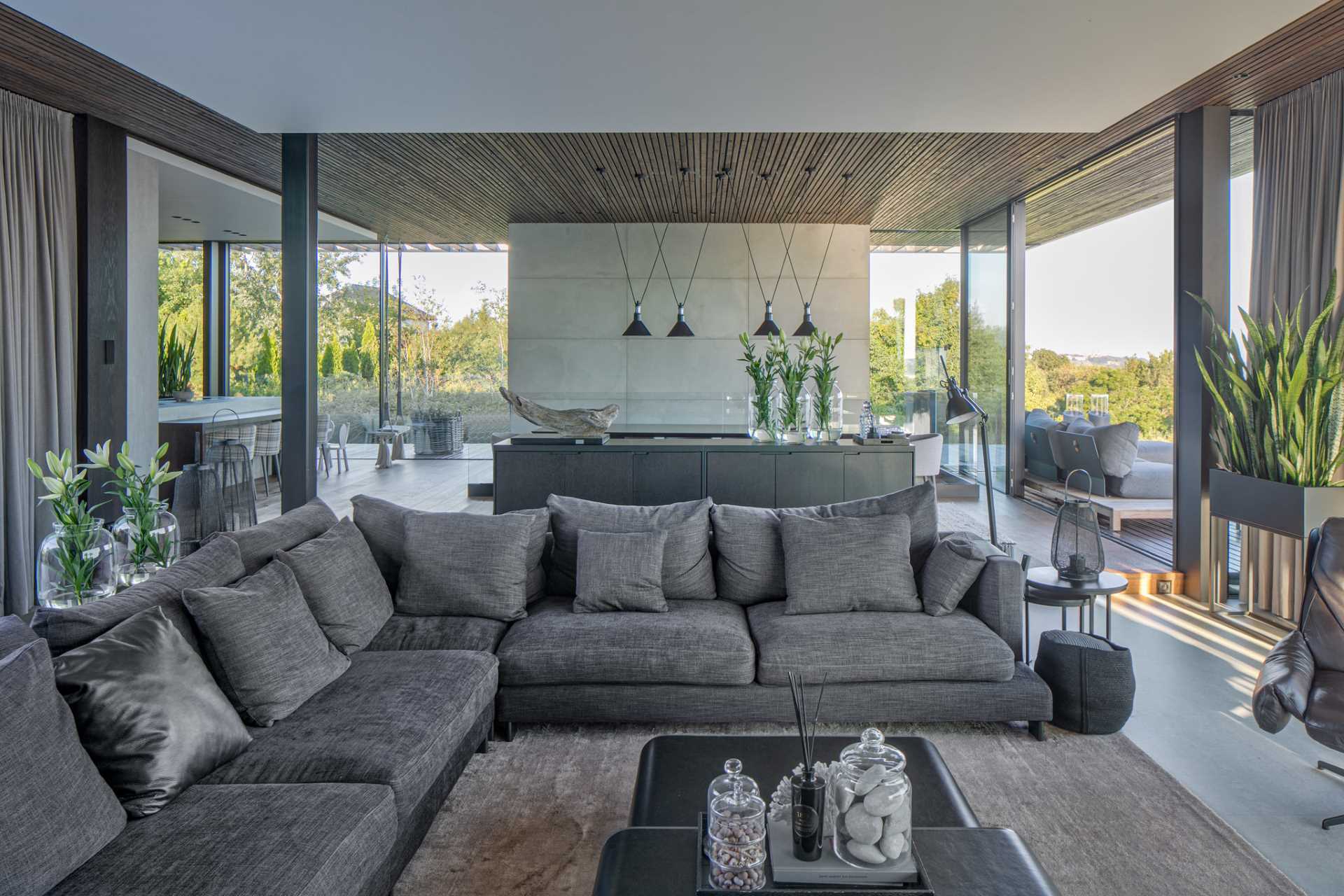 A modern living room that shares the open plan design with the dining room and a nearby kitchen.