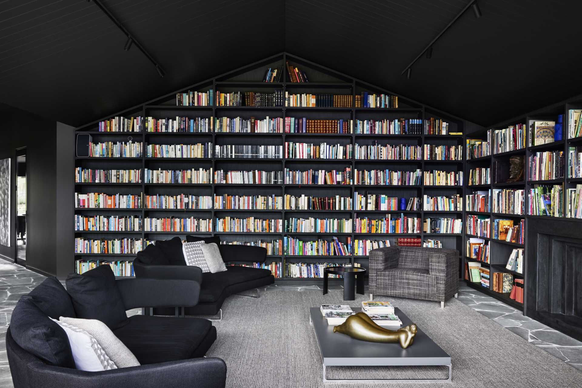 A modern living room with an abundance of bookshelves and a fireplace.