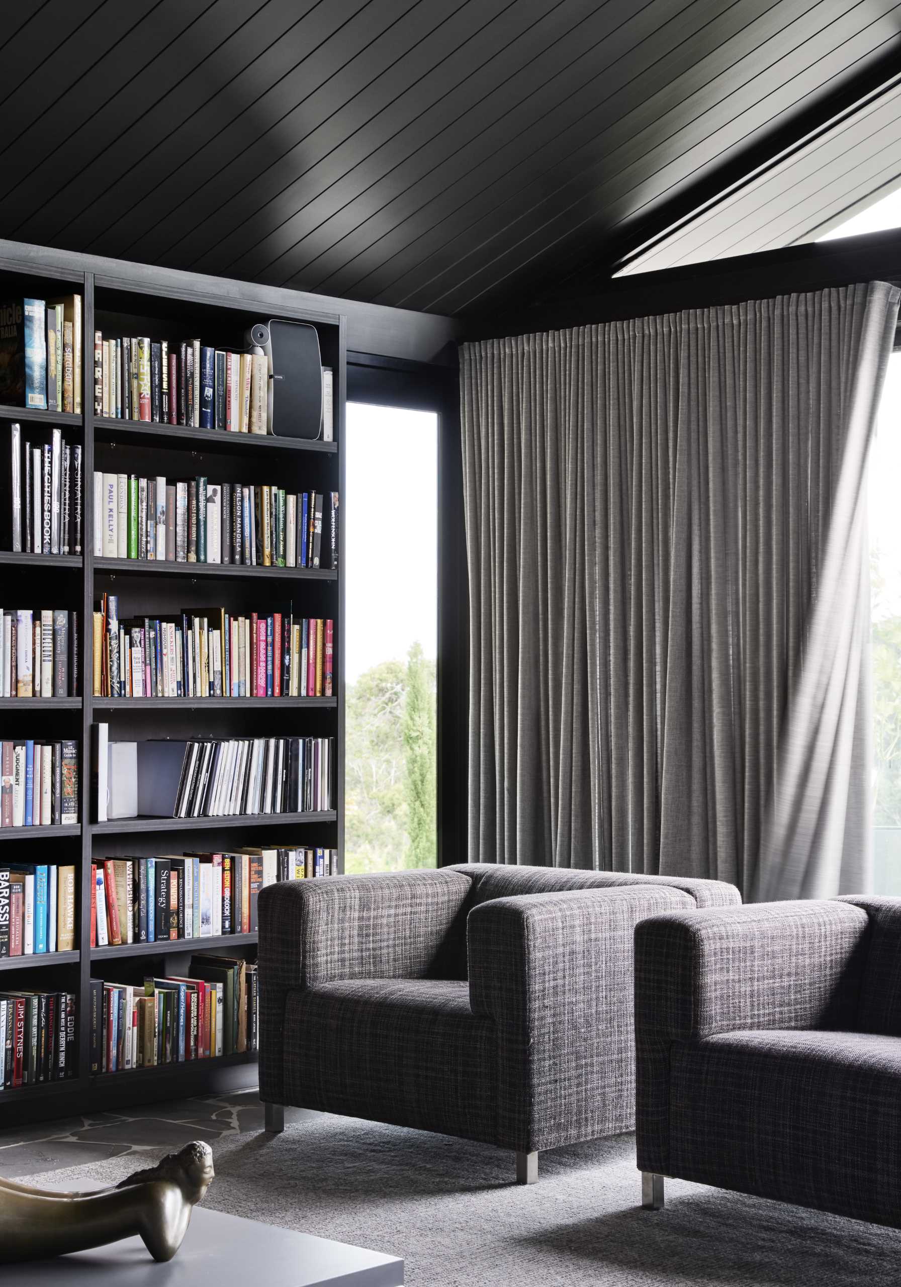 A modern living room with an abundance of bookshelves, and a dark and moody interior.