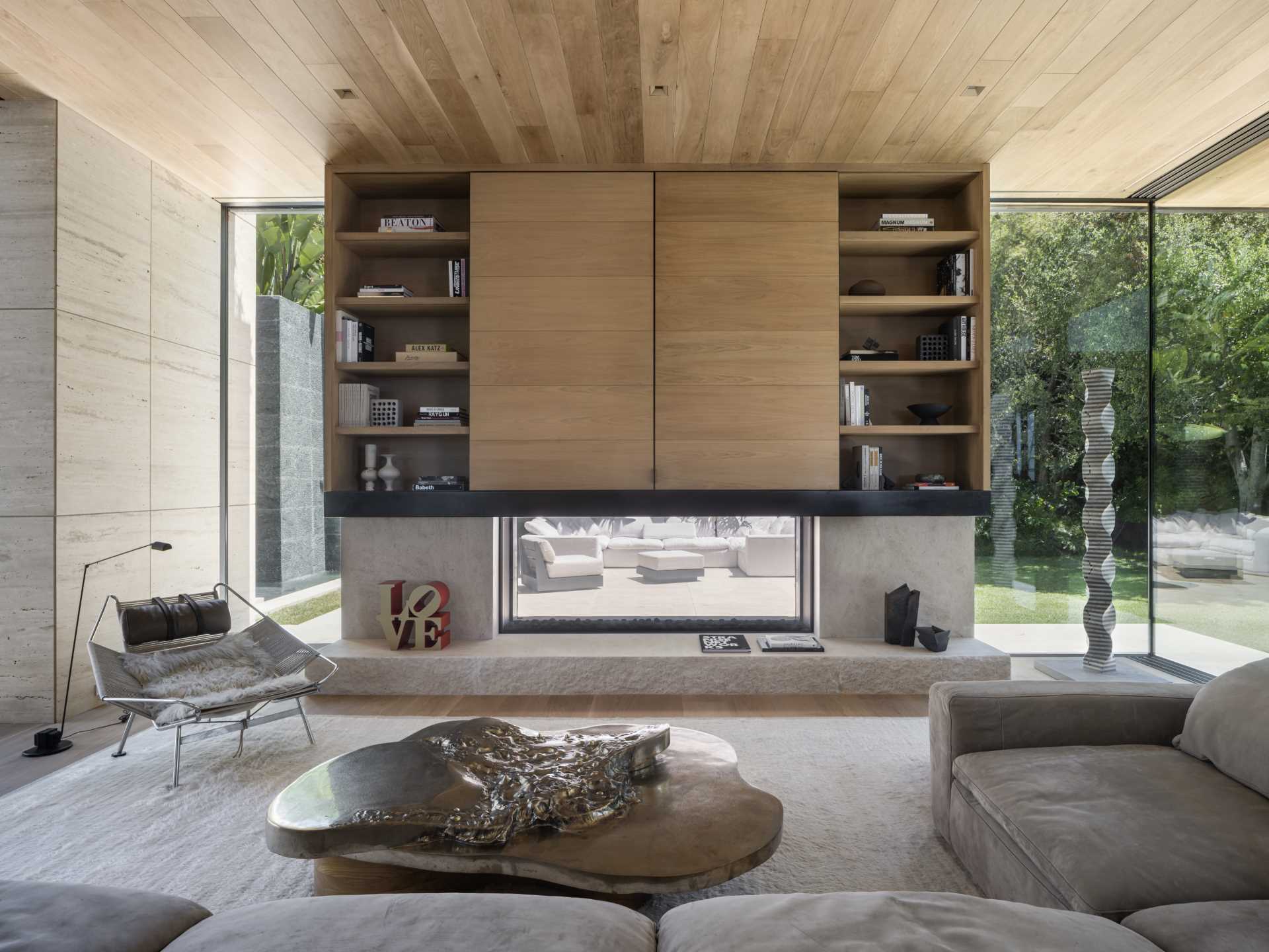 A living room with see-through fireplace with wood shelving above and floor-to-ceiling windows.