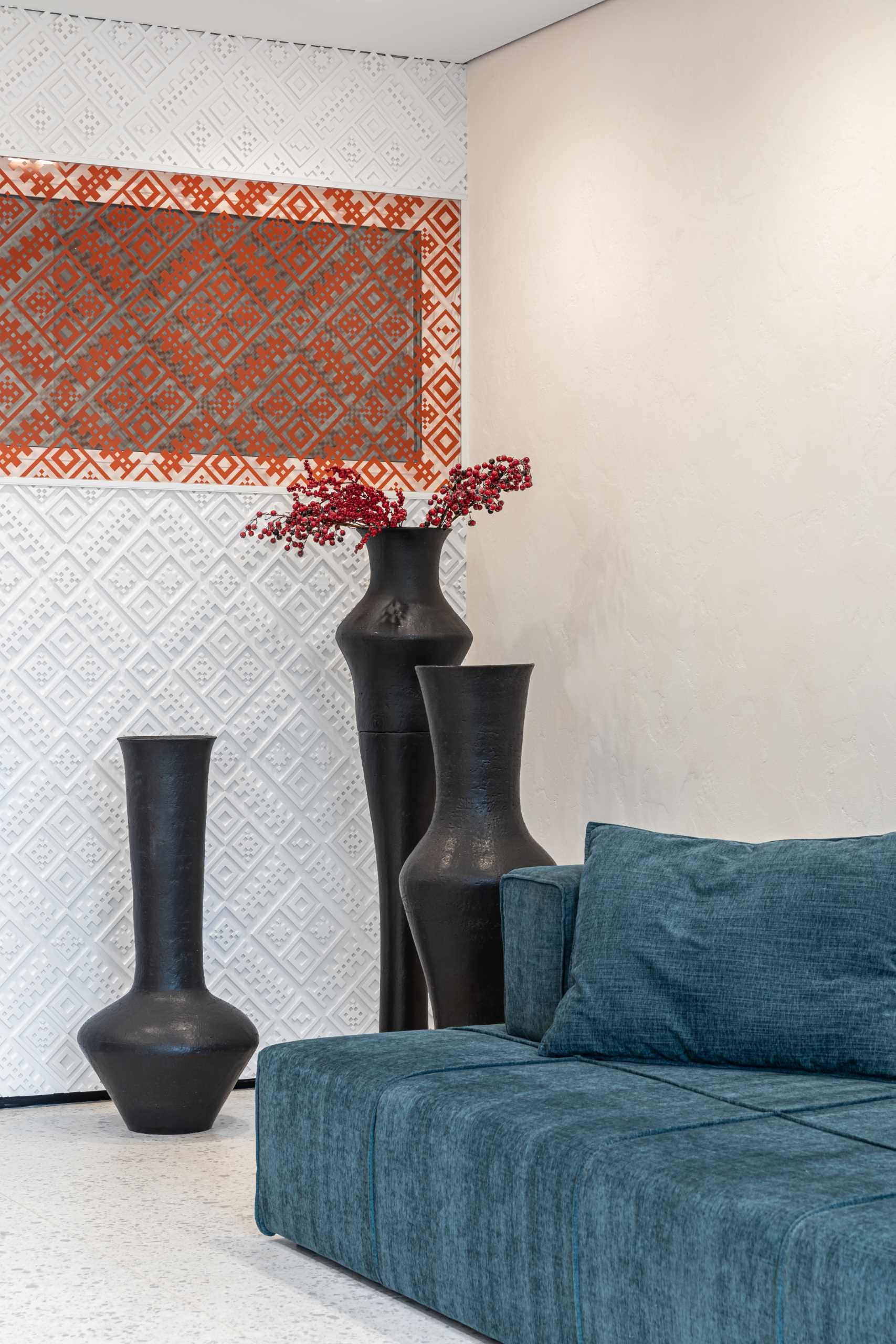 A delicate pattern on the wall transitions from white to red, while a large mirror reflects the turquoise couch.