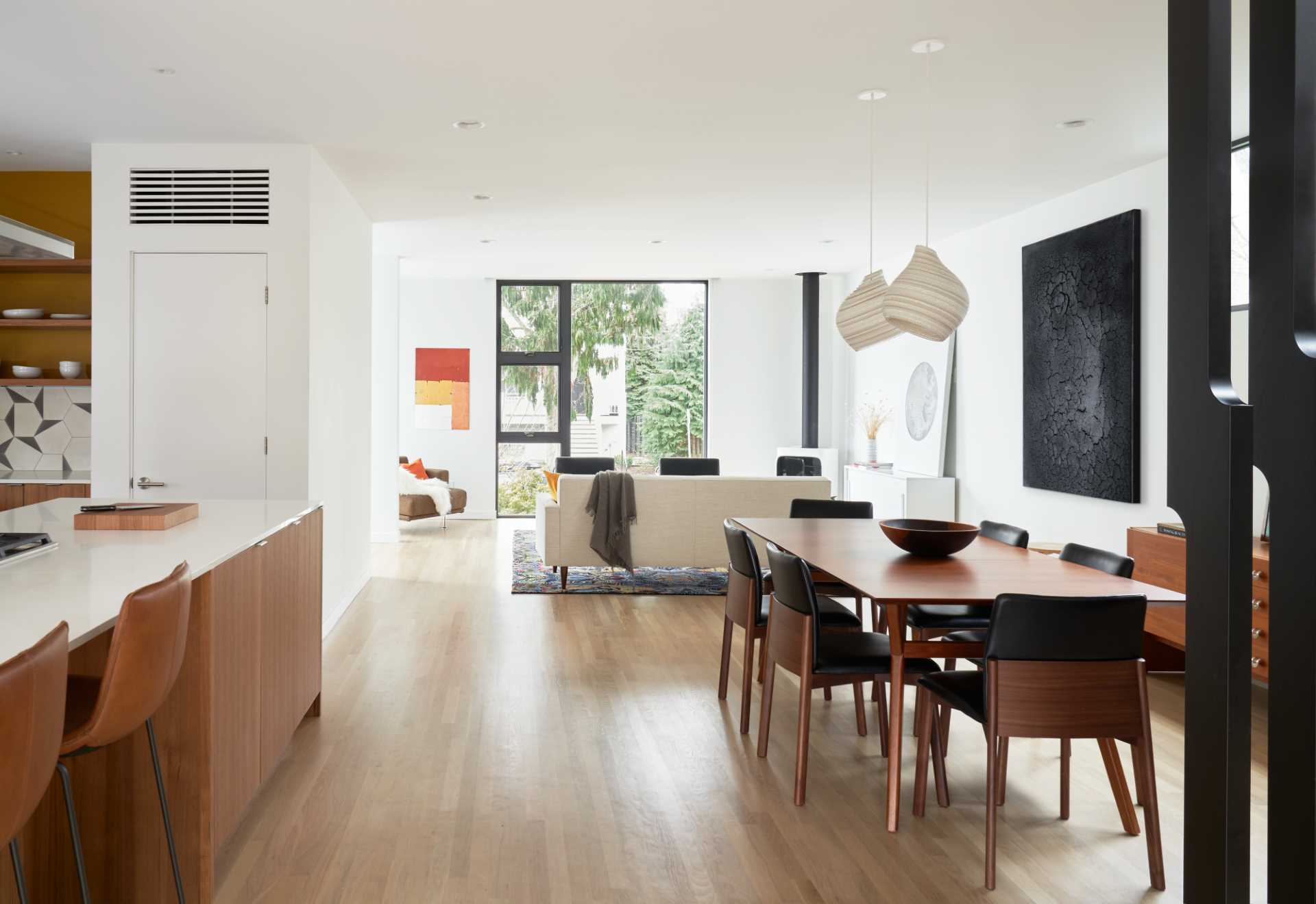 A modern dining room with a warm wood table and a pair of sculptural pendant lights.