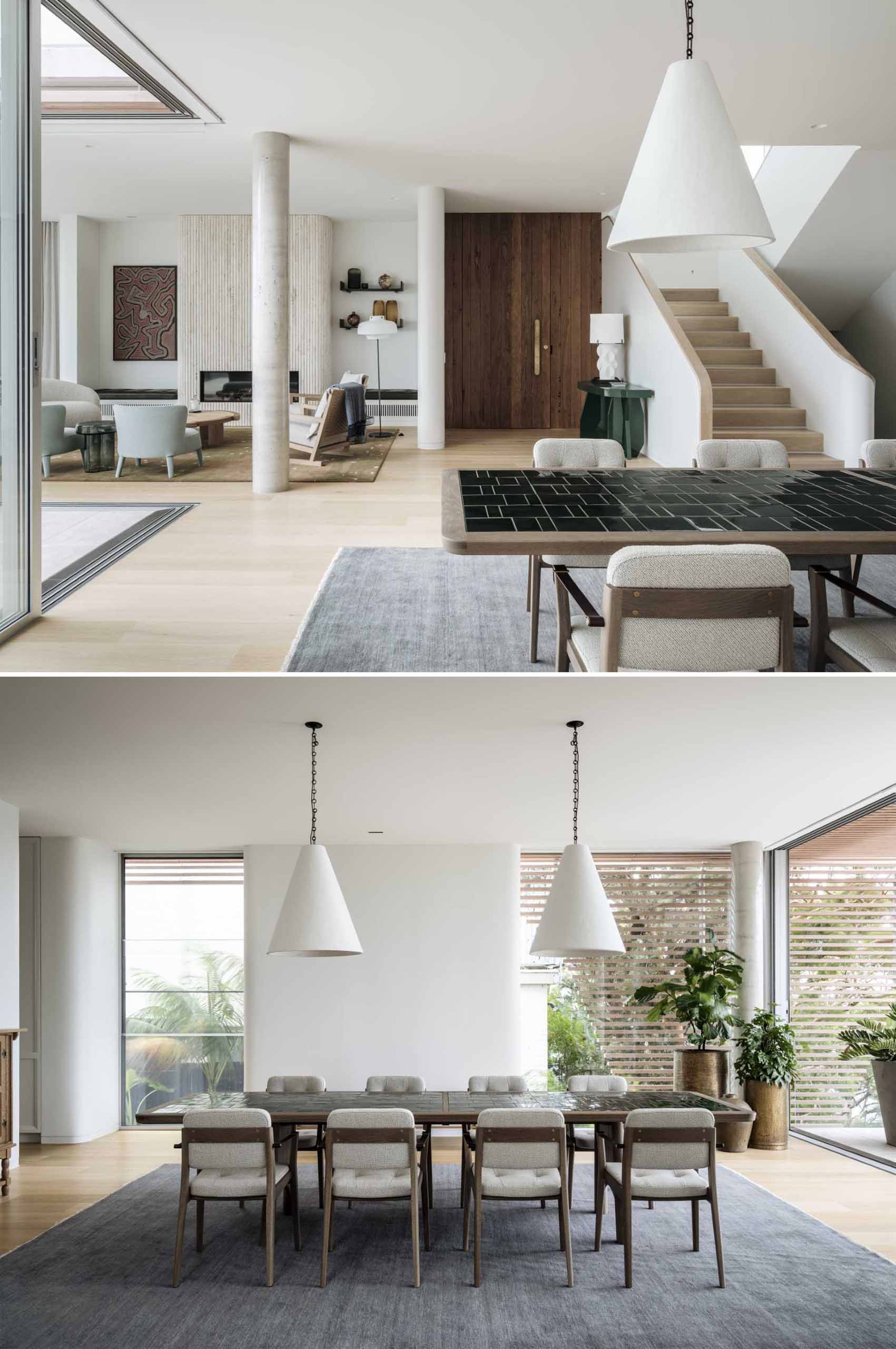 This contemporary dining room includes a large table surrounded by chairs, with two pendant lights hanging above, and a rug to help anchor the table in the open space.