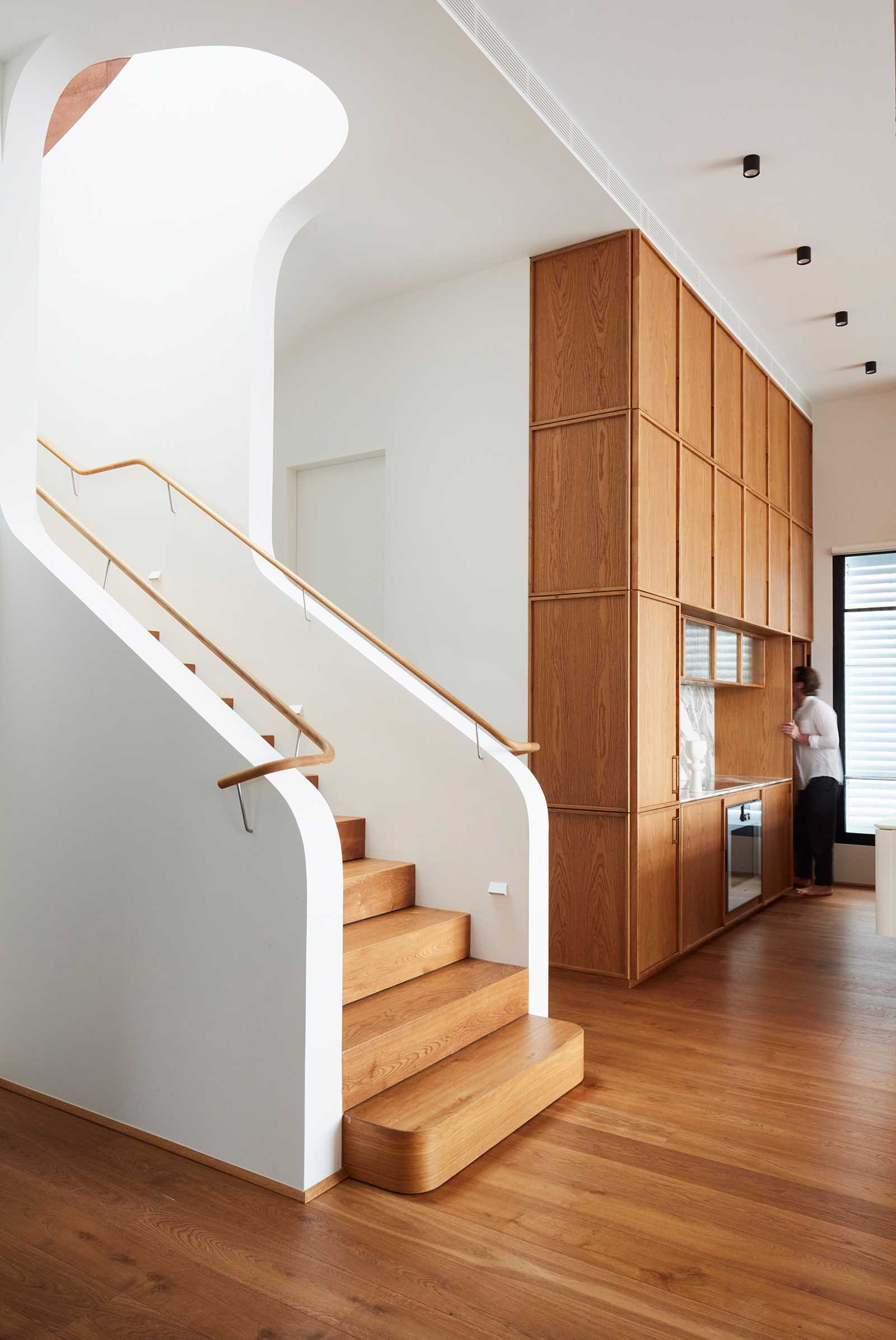 A modern home with a wood kitchen that matches the wood stairs.