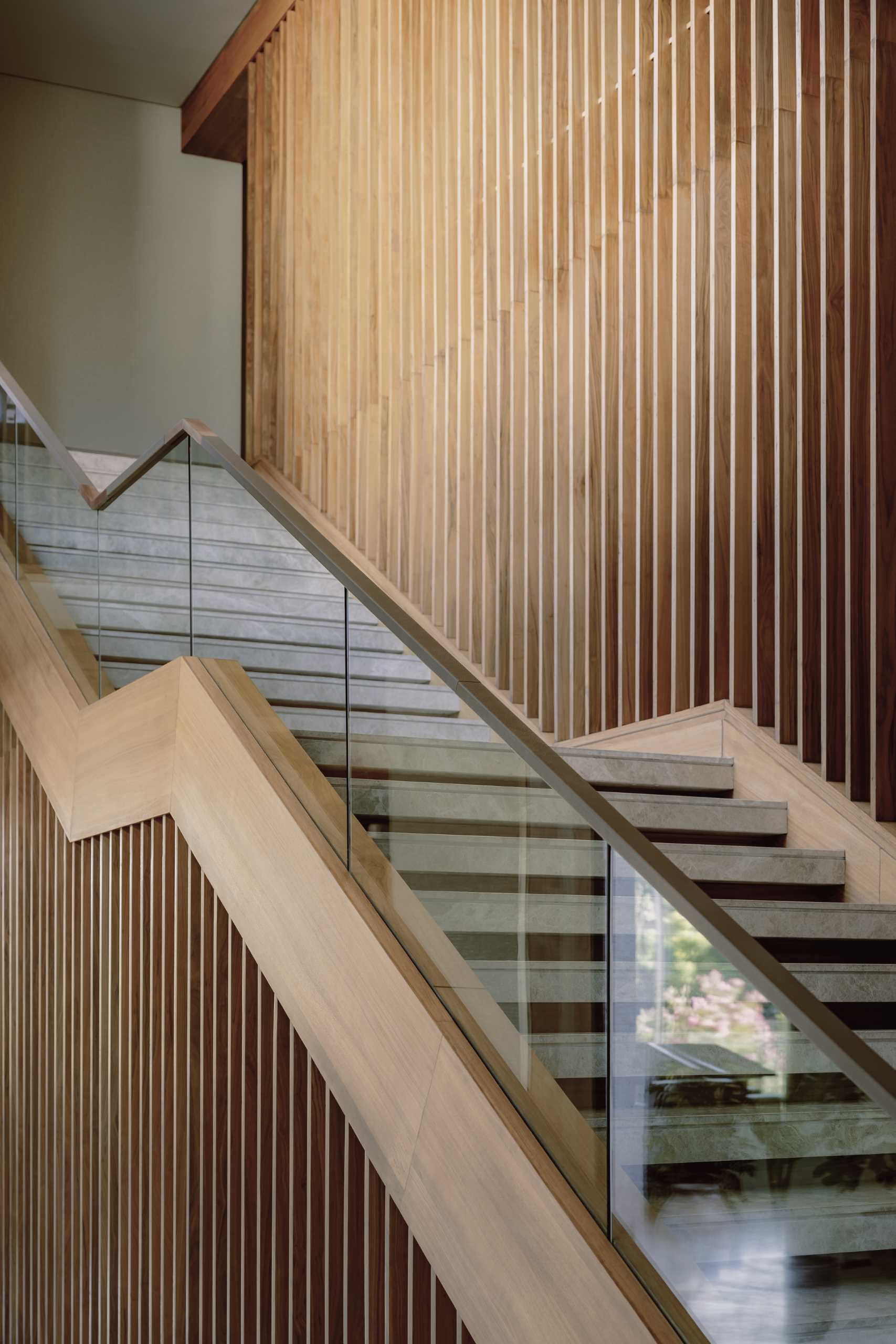 A modern home with a staircase that includes a glass and wood handrail.