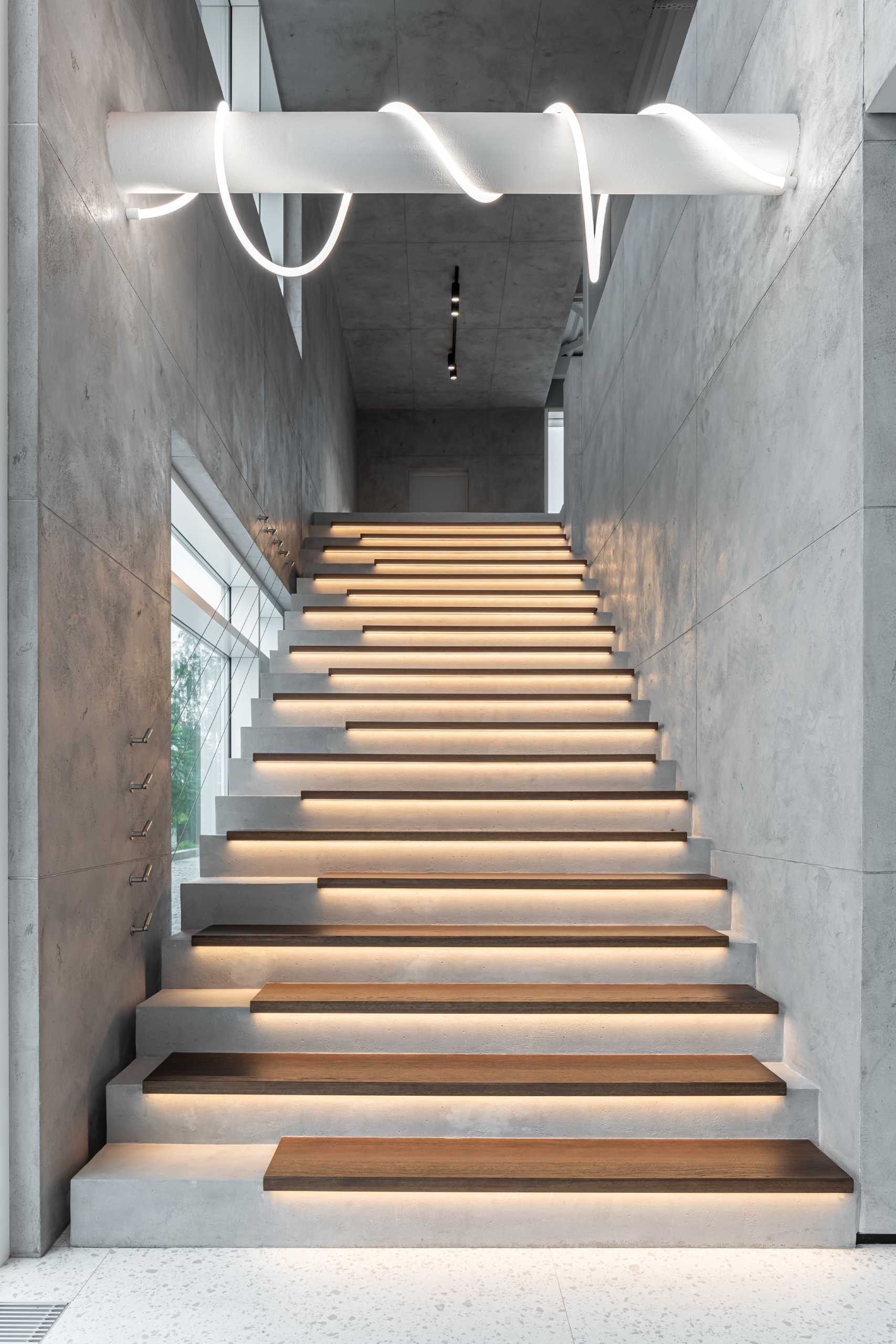 A modern home with concrete and wood stairs, that also include hidden lighting underneath the treads
