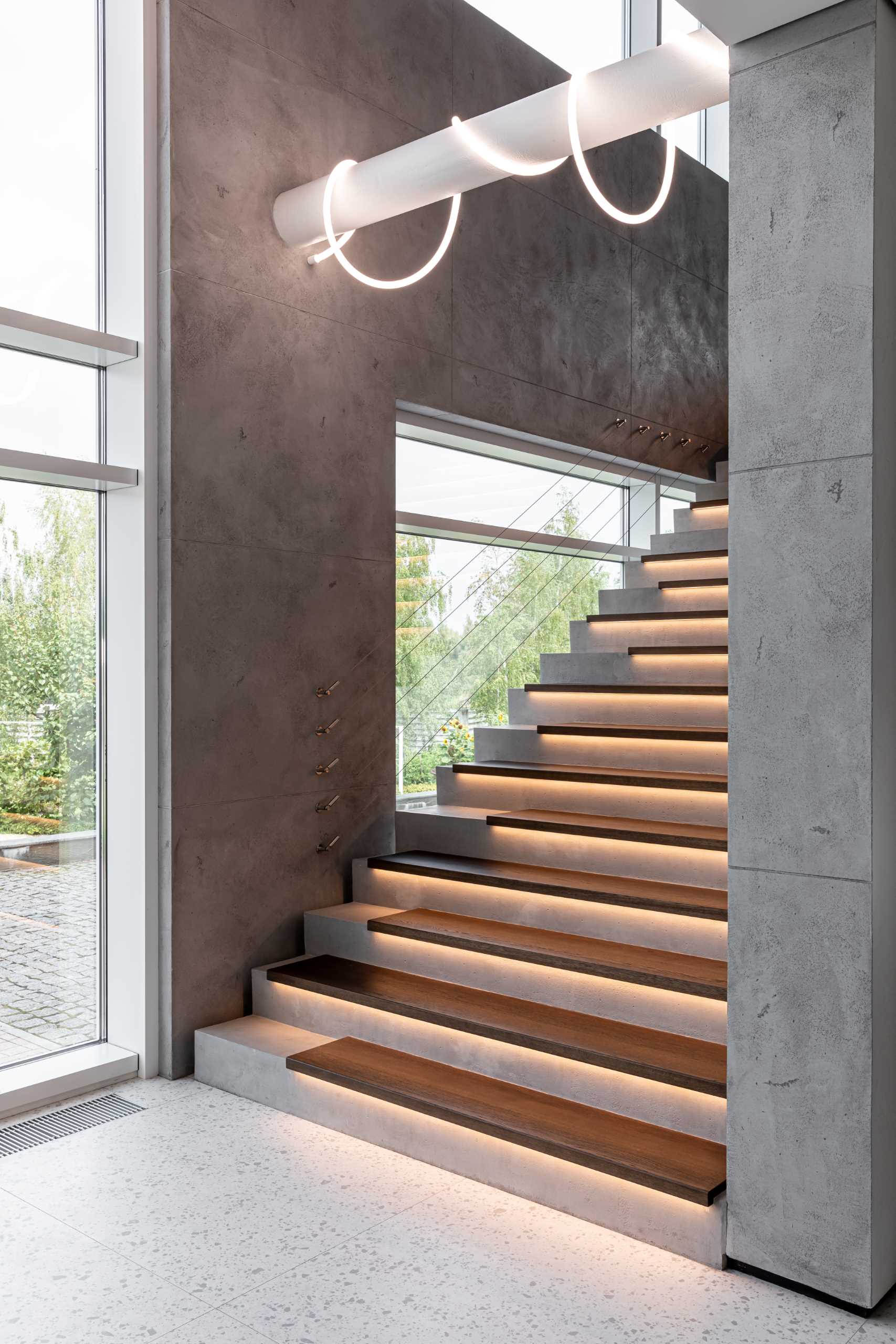 A modern home with concrete and wood stairs, that also include hidden lighting underneath the treads