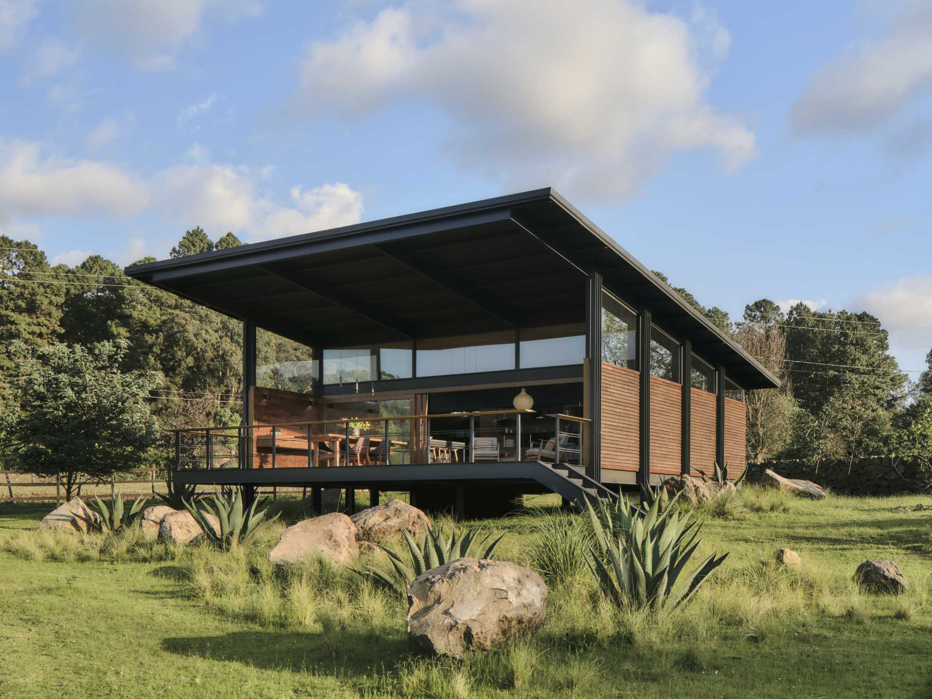 A modern tiny house with a sloped roof and large covered terrace.