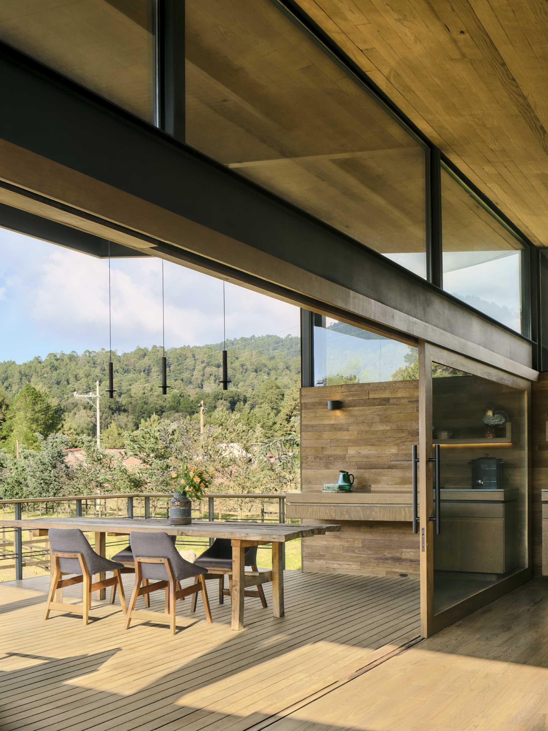 Large sliding doors connect the living room and kitchen of this small house with a large terrace.