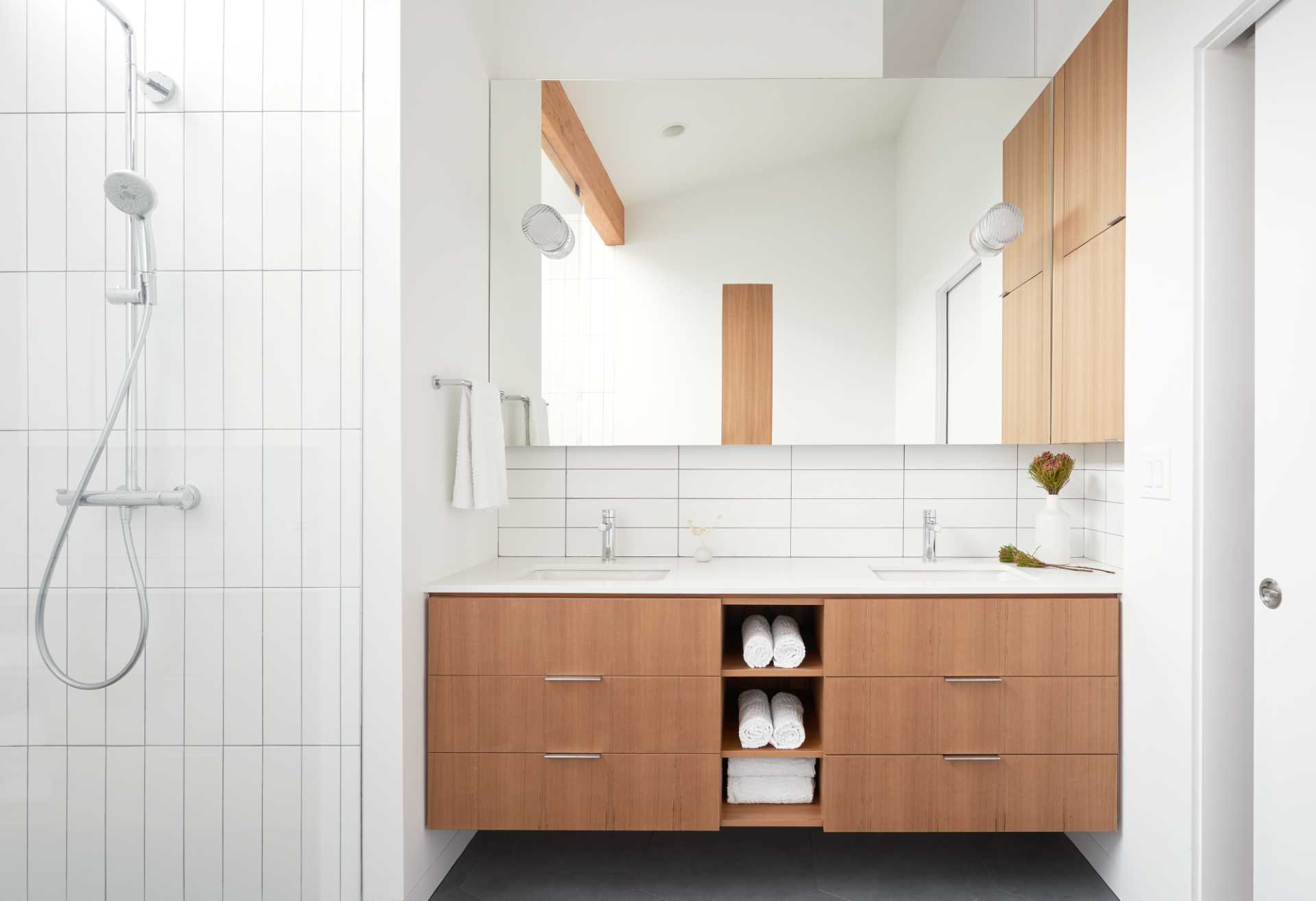 A modern wood and white bathroom with a shower that includes a shelving niche.