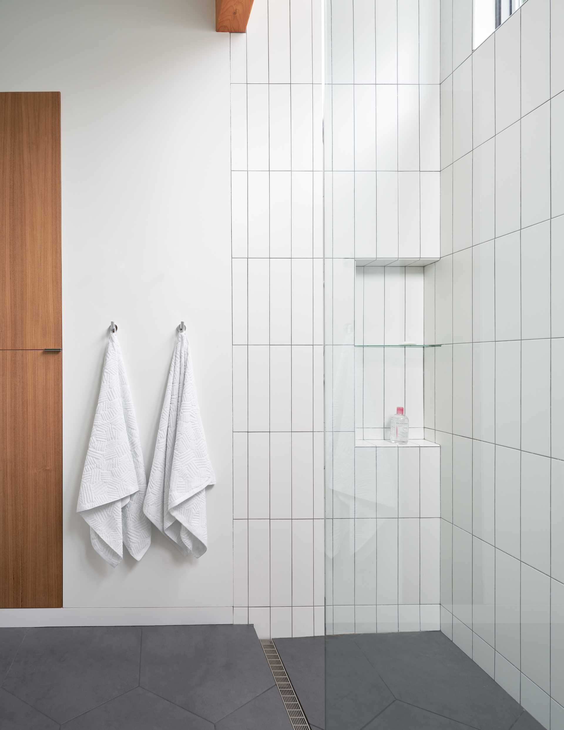 A modern wood and white bathroom with a shower that includes a shelving niche.
