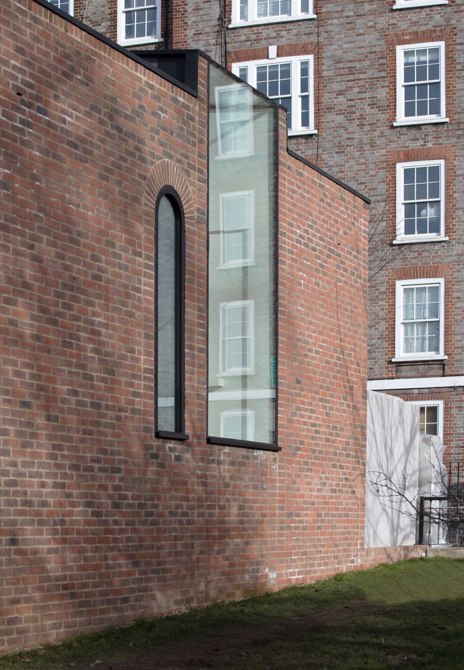 A brick townhouse with an arched window and a large rectangular window.