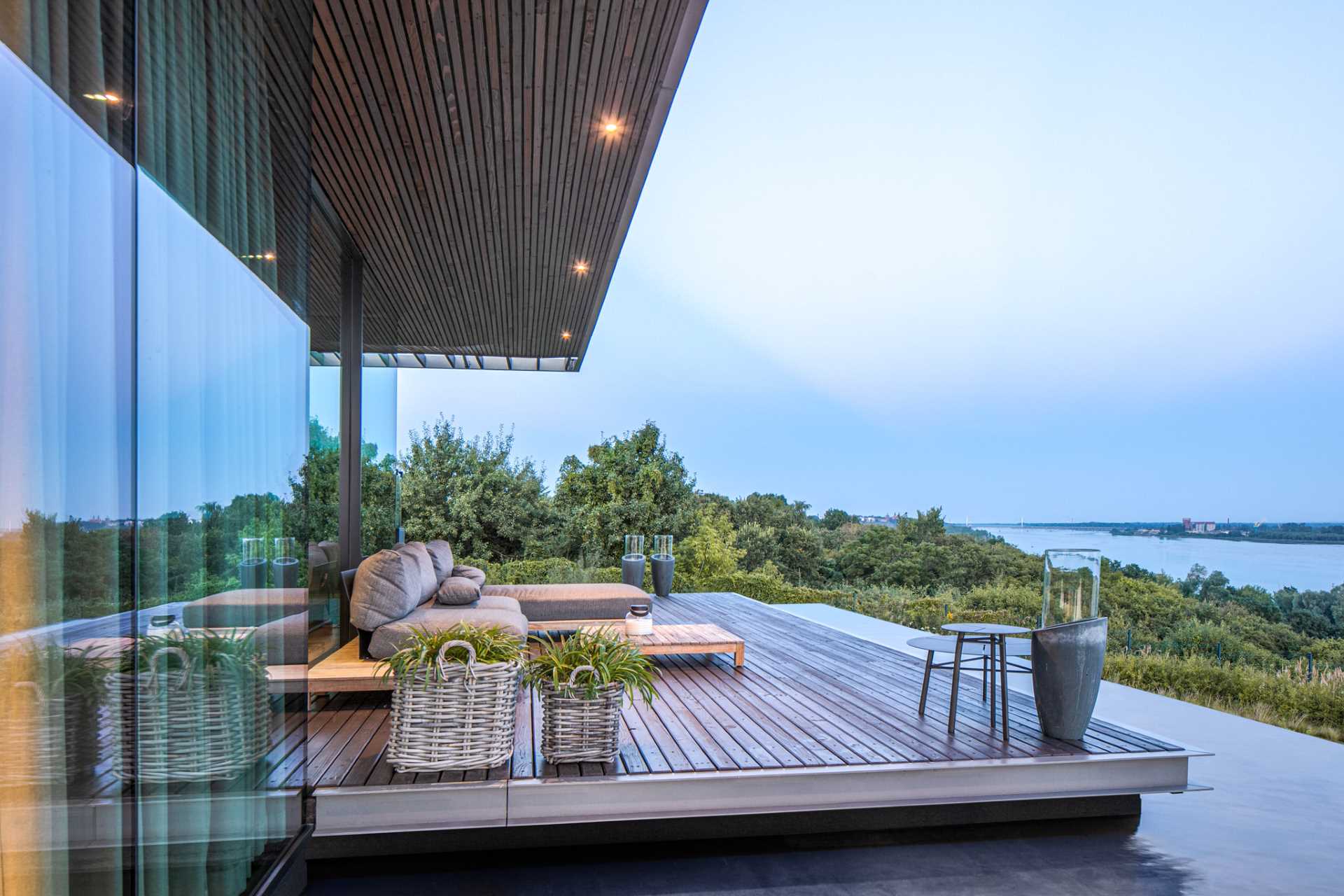 A modern home with a wall of windows, a deck, and a water feature.