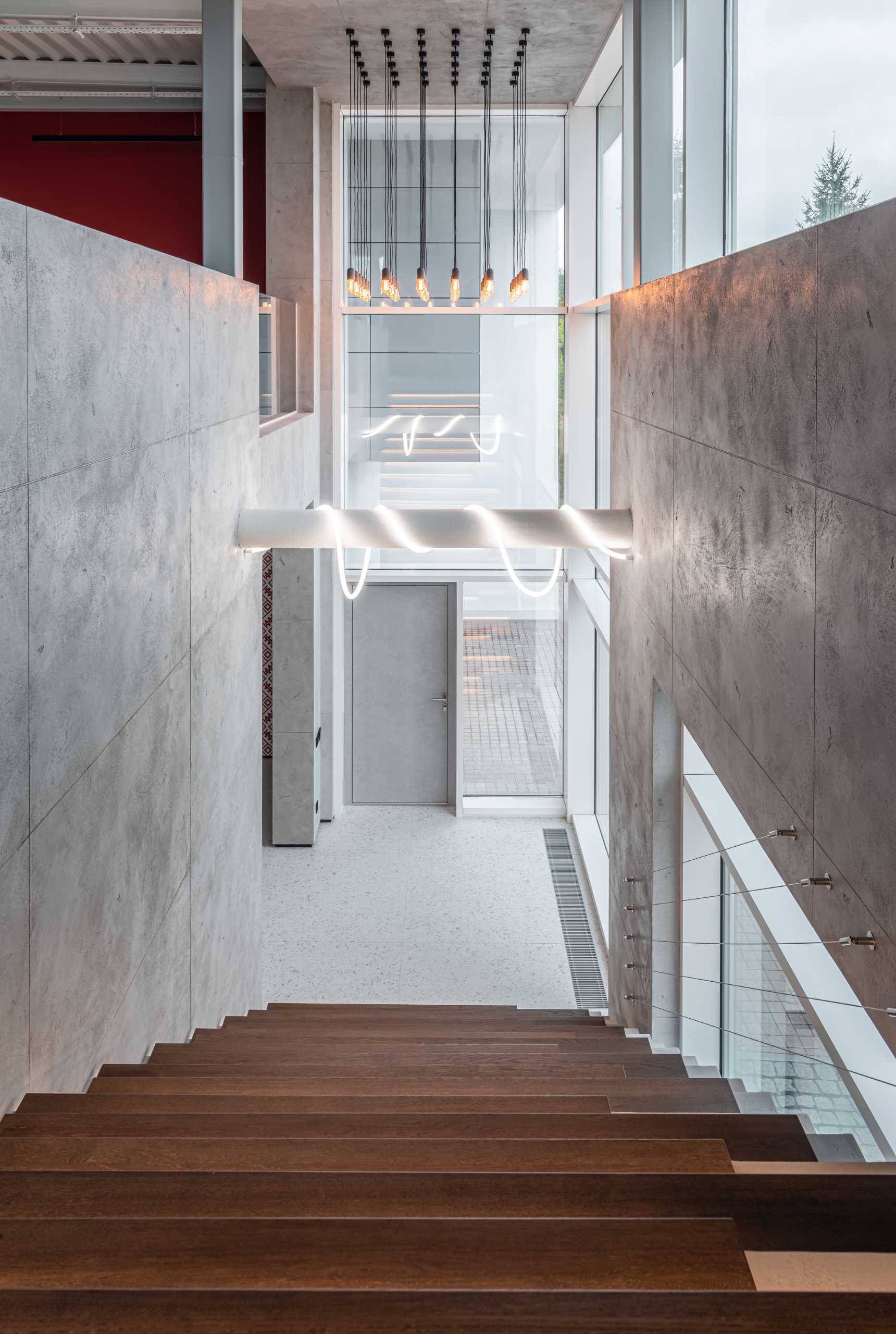 A modern home with concrete walls and multiple light installations that draw attention to the high ceiling.