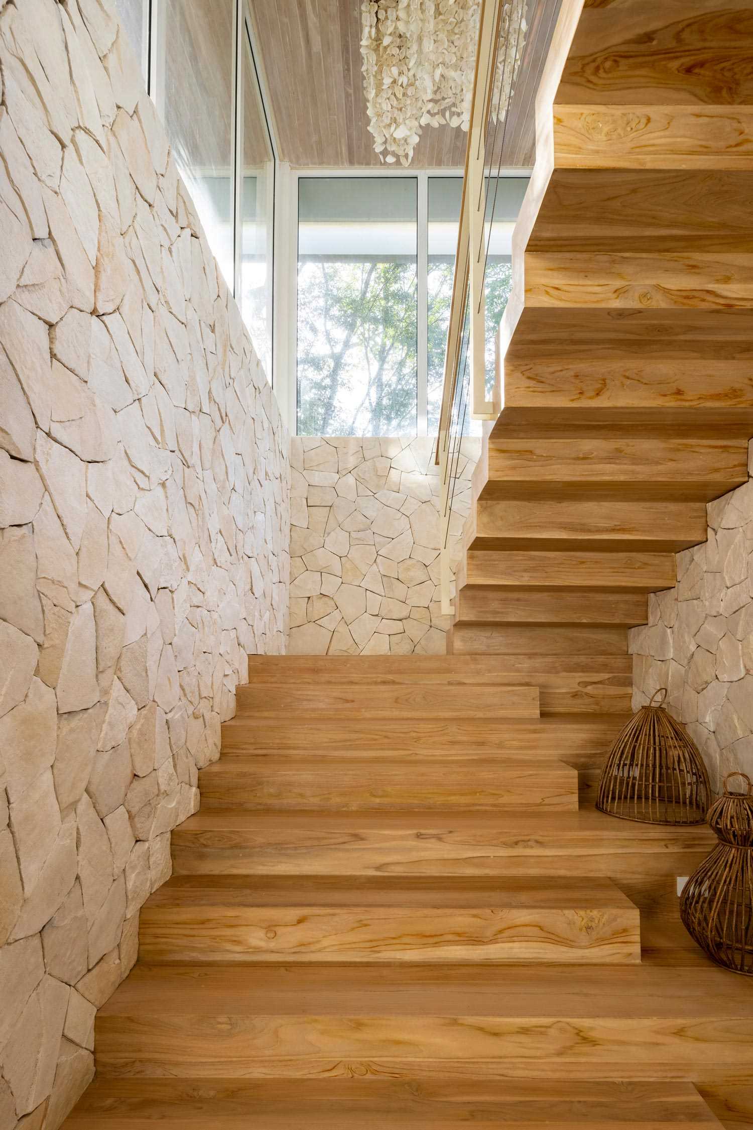 Modern wood stairs surrounded by stone walls and windows.