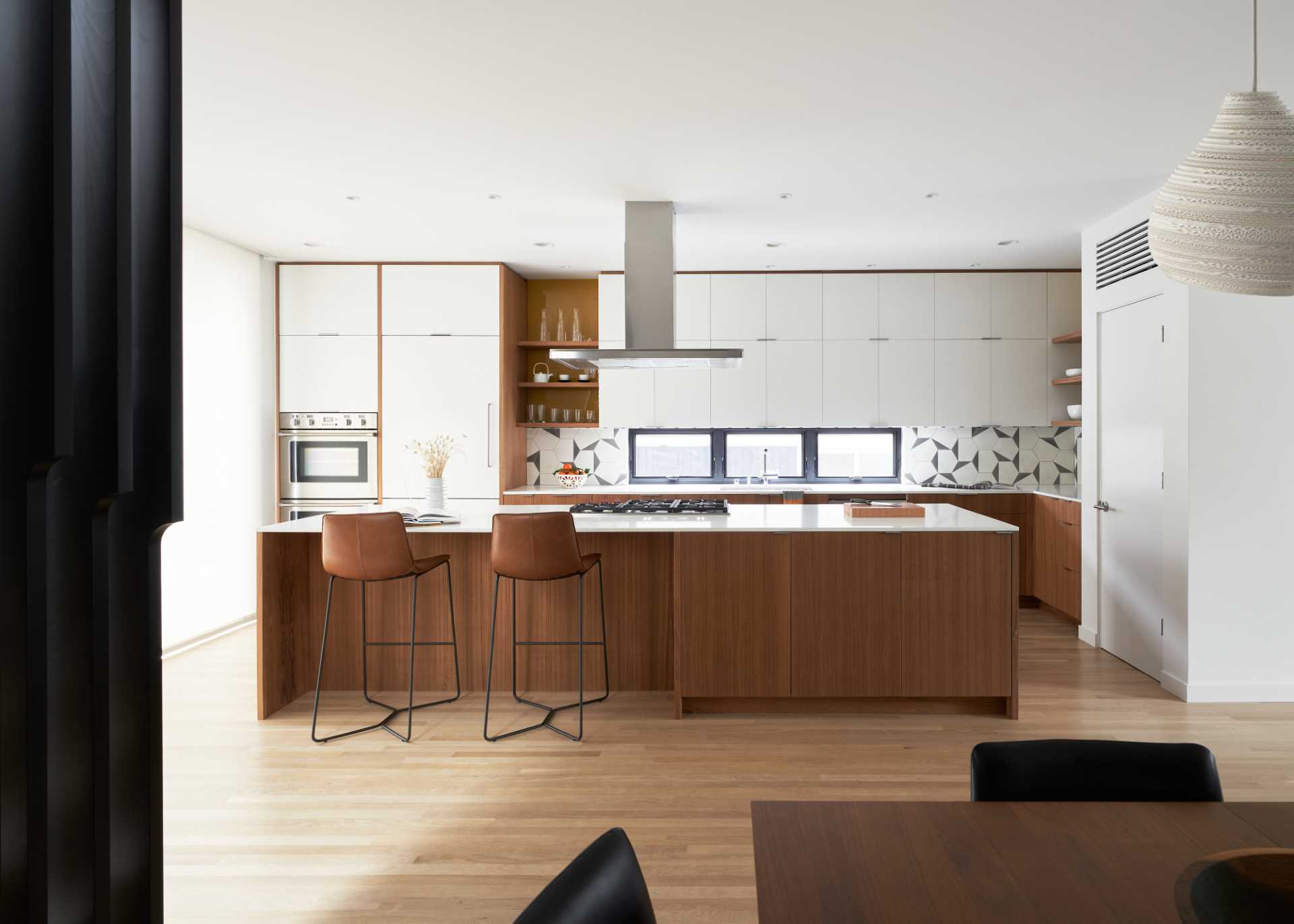 A modern white and wood kitchen with a large island.