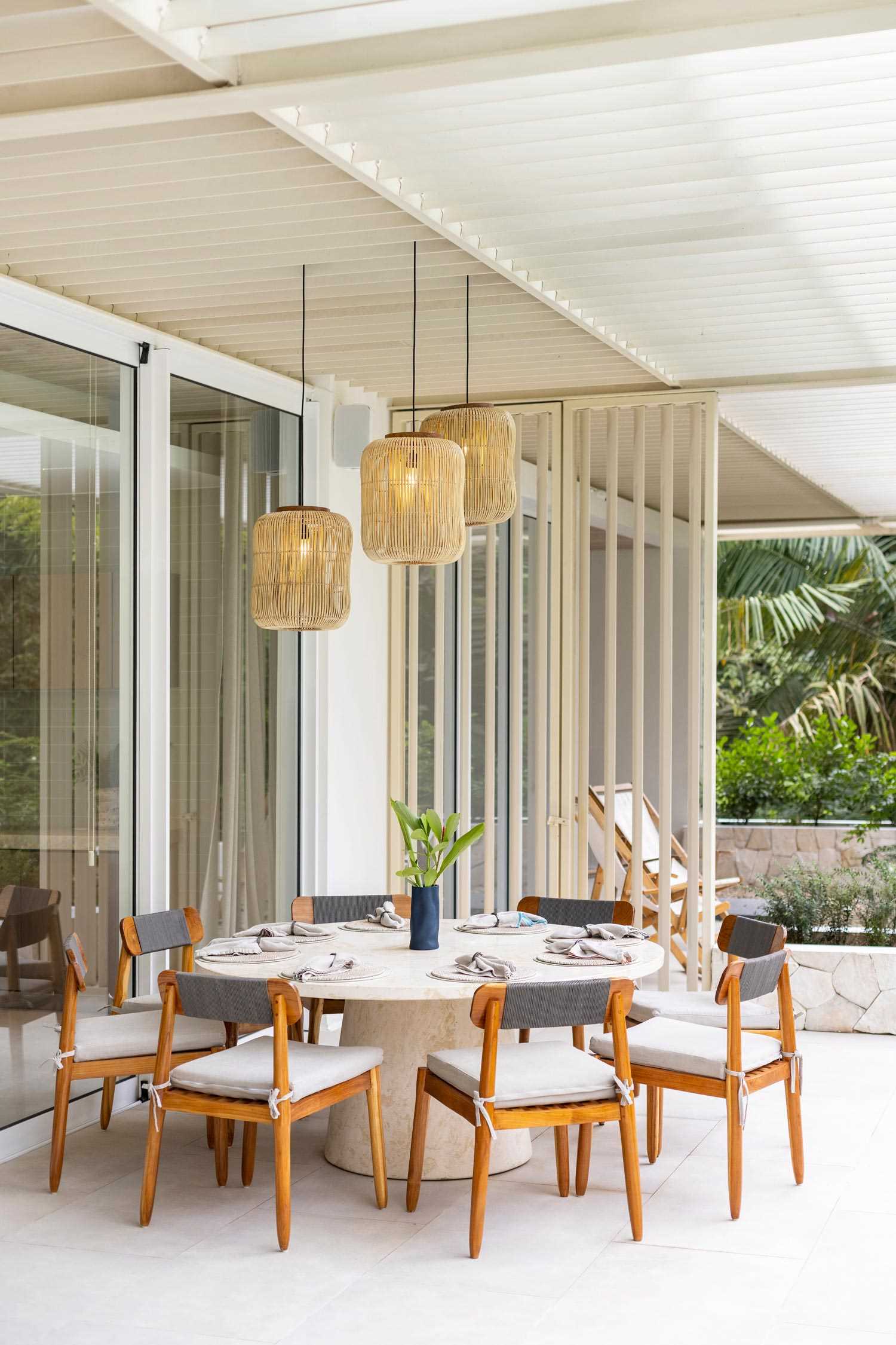 A covered outdoor dining area located off the kitchen has views of the pool.