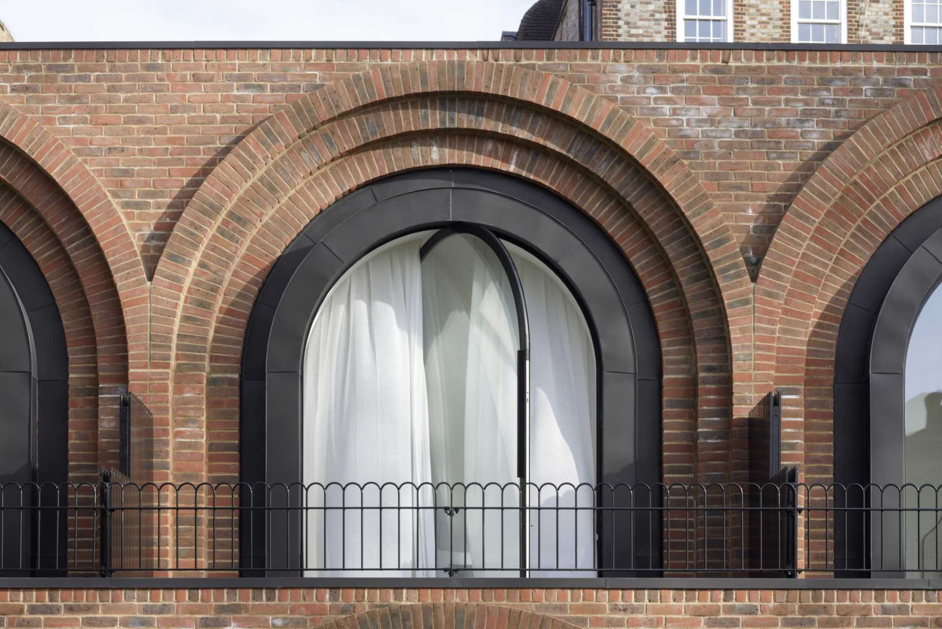 A modern bedroom with a pivoting arched window with a black frame.